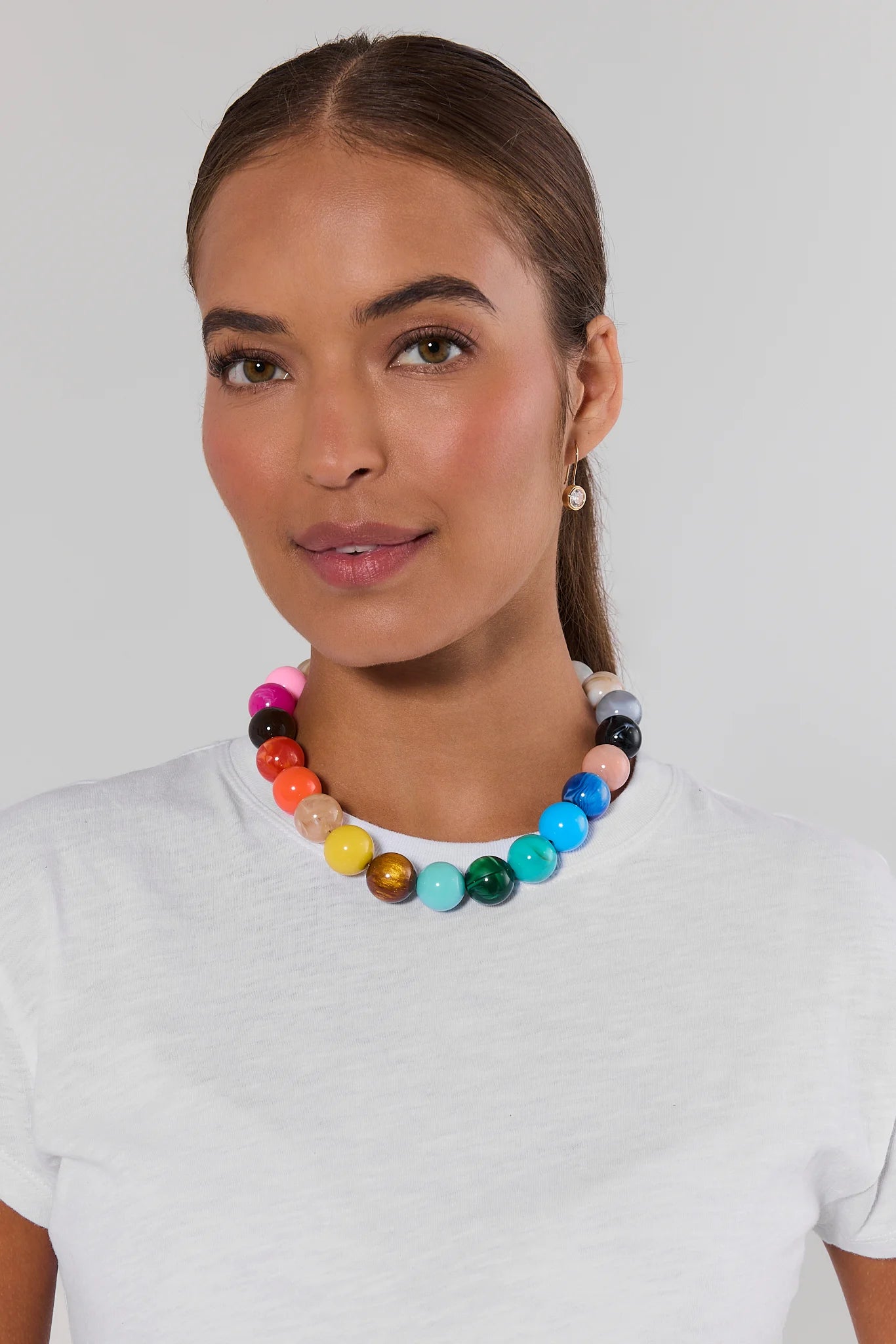 woman wearing multi colored rainbow beaded necklace on white background