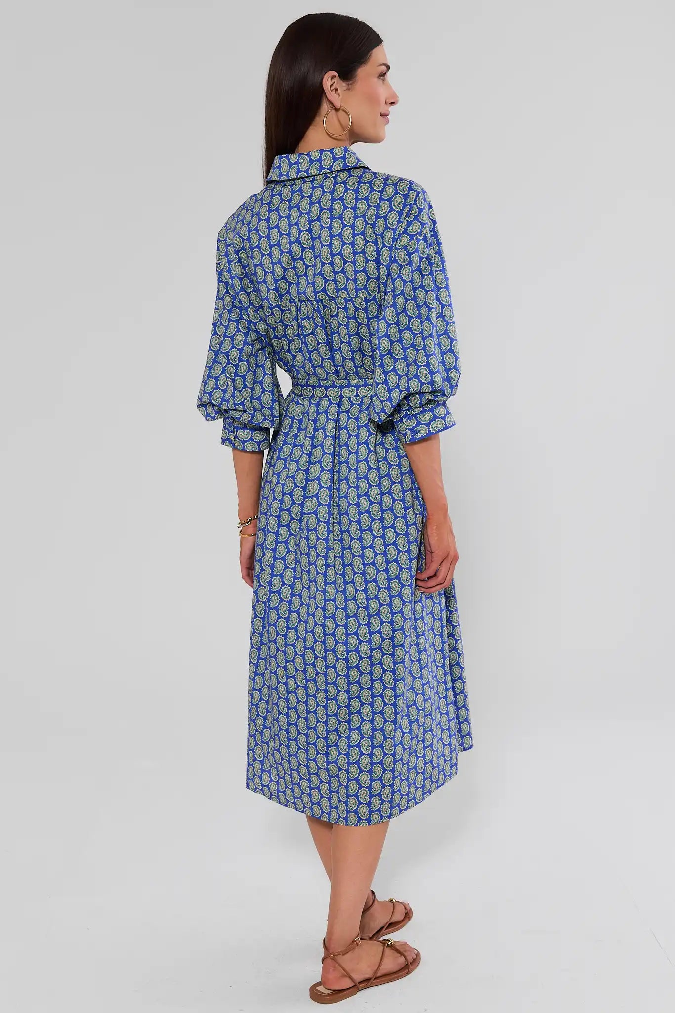 A woman standing in a blue midi shirt dress with a yellow geometric pattern, shown against a light studio background.
