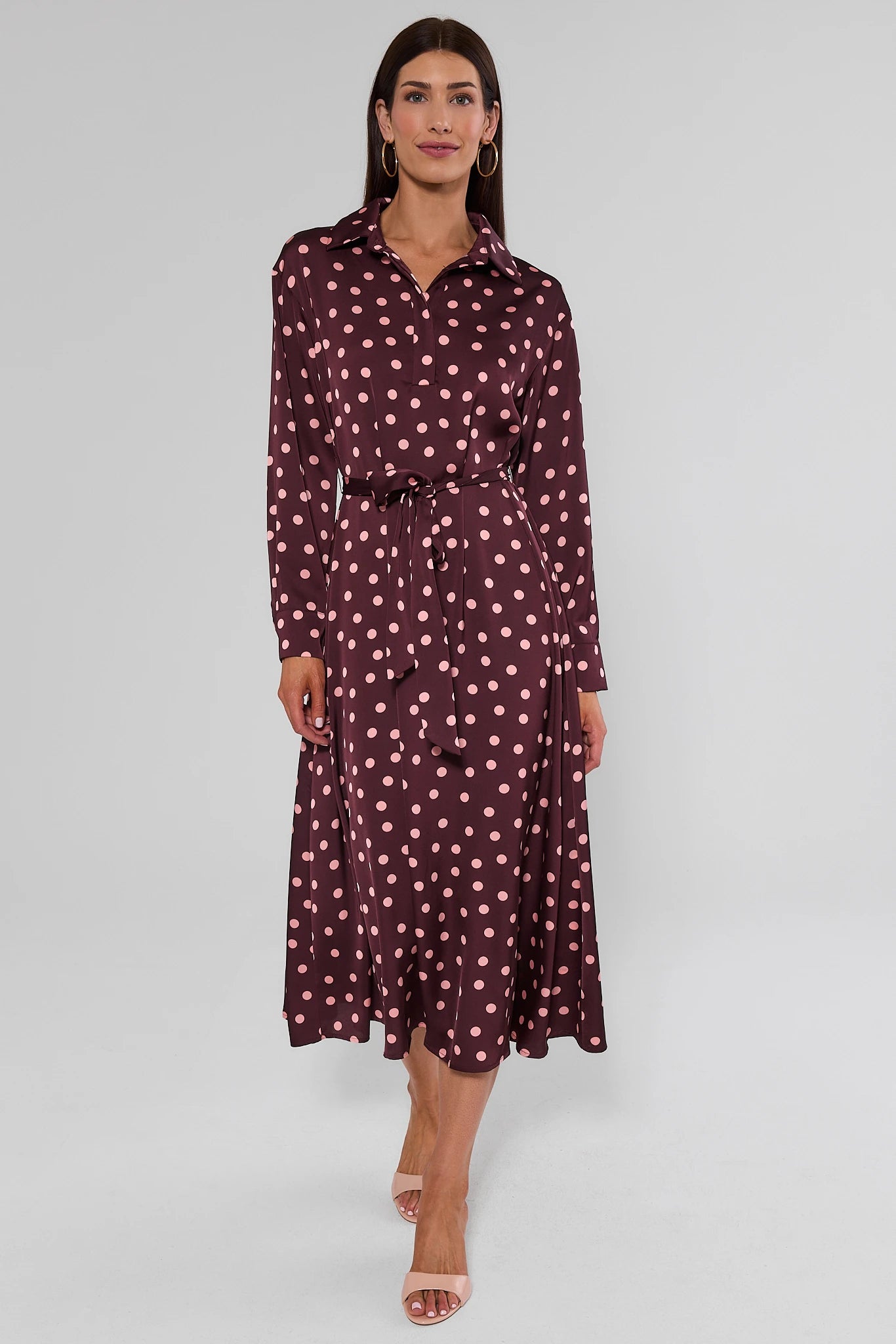 woman wearing brown polka dot dress on white background walking