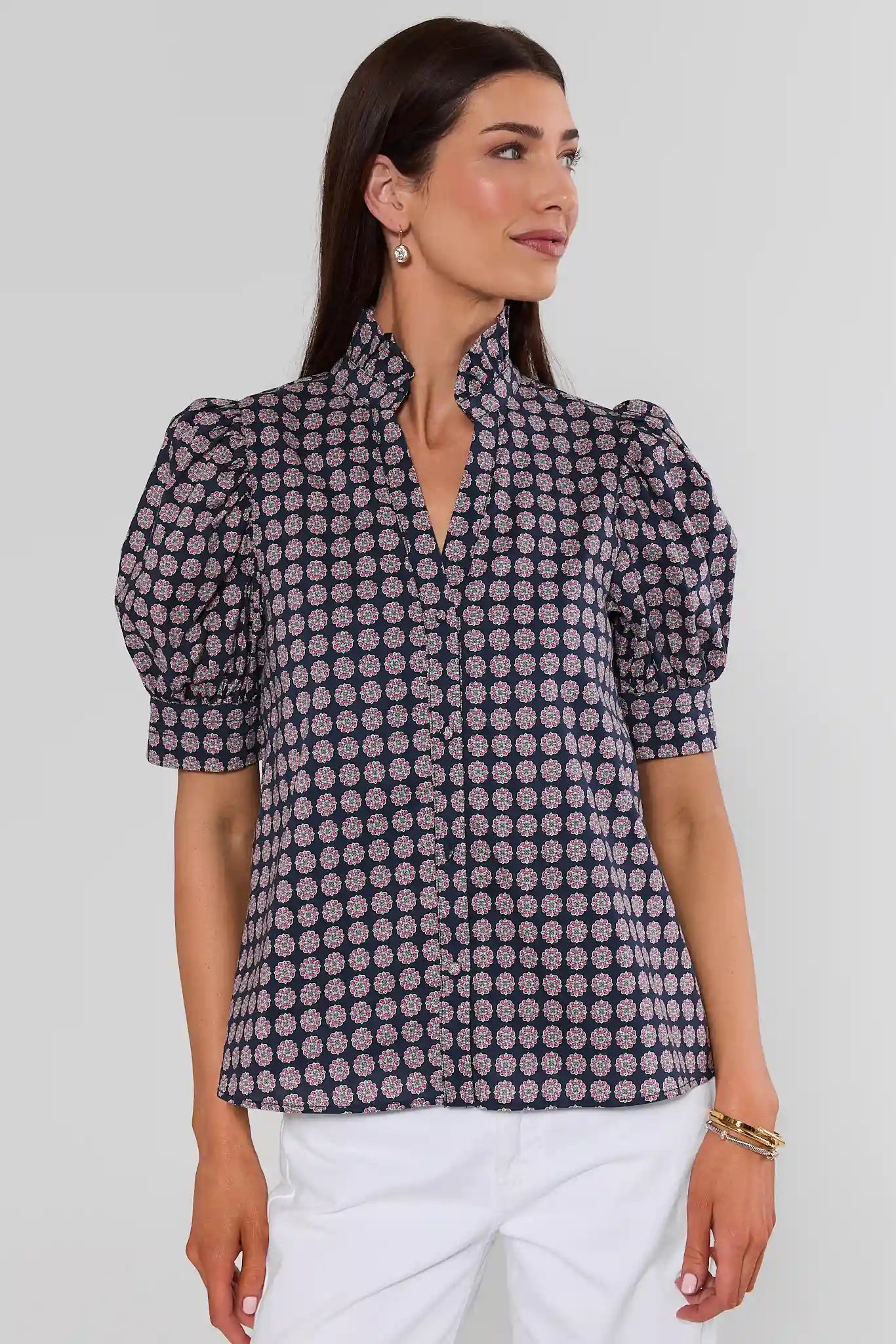 Woman wearing a geometric navy and purple top with white jeans on a white background