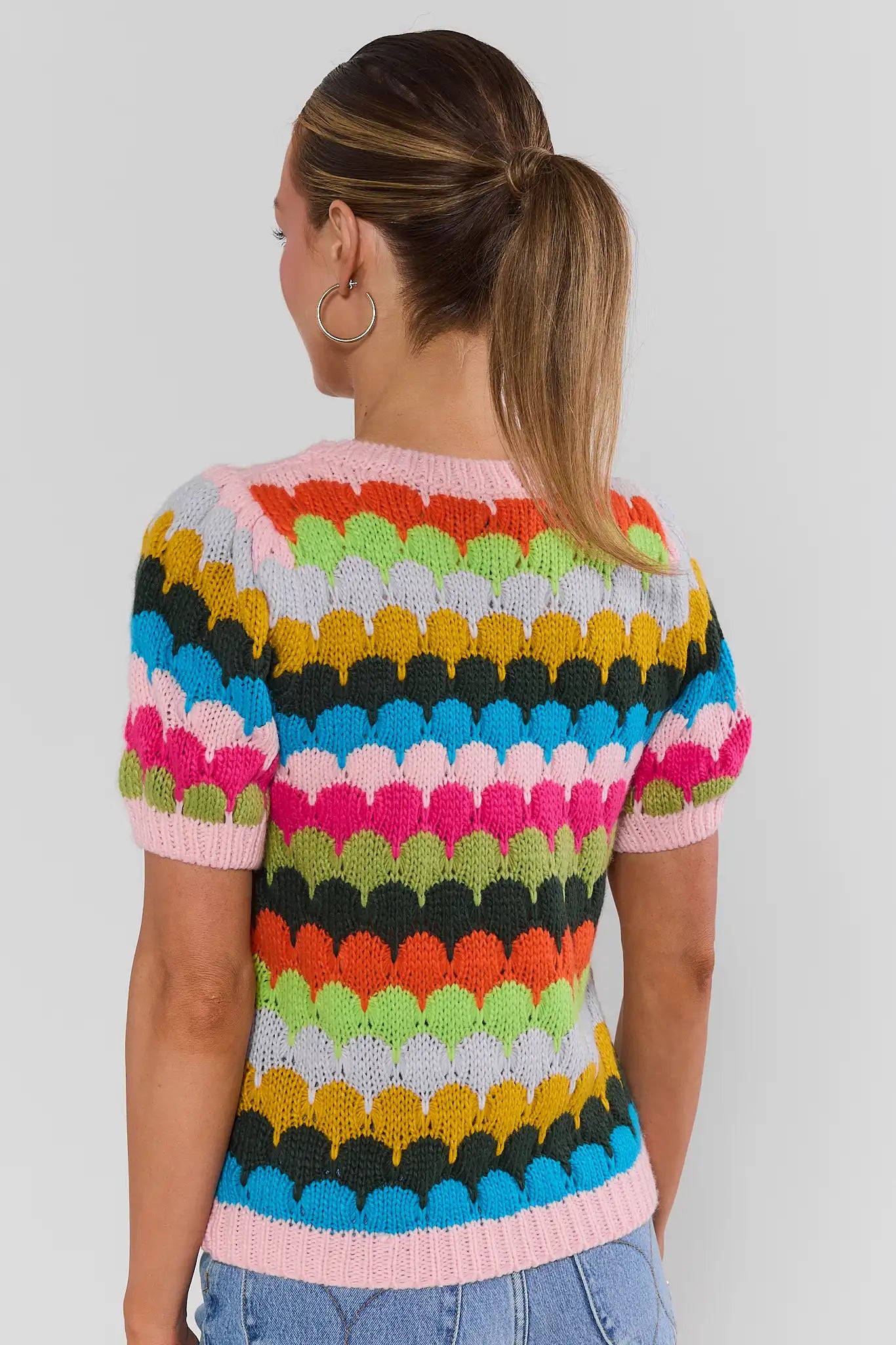 woman standing wearing trina multi striped knit top with jeans on a white background