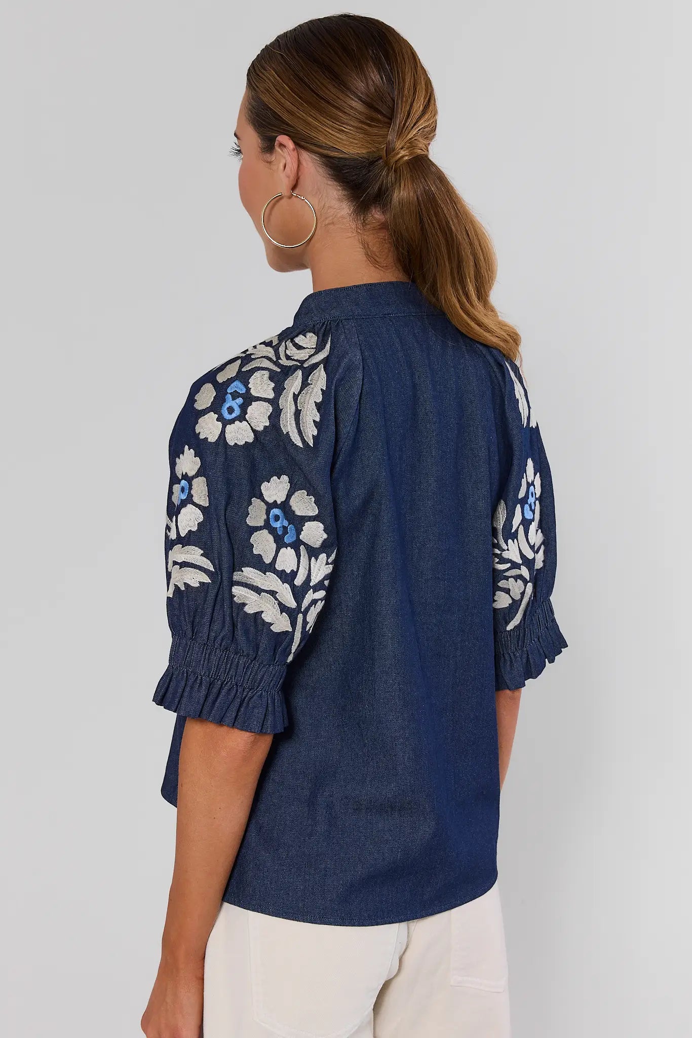 Woman wearing Navy Floral Embroidered Top by THML on a white background standing backwards