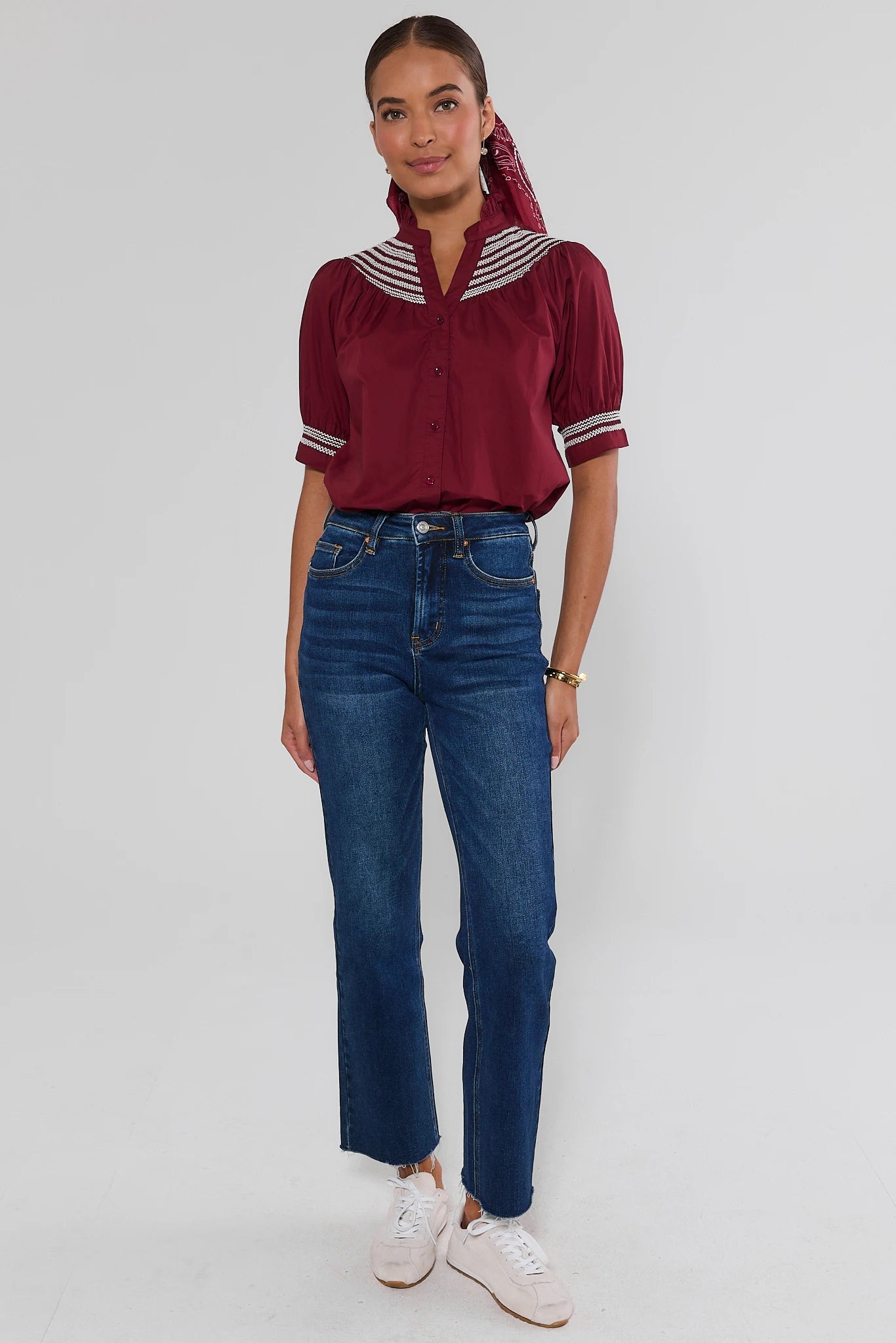Woman wearing Yvonne Burgundy and White Embroidered Top and dark becca jeans on a white background