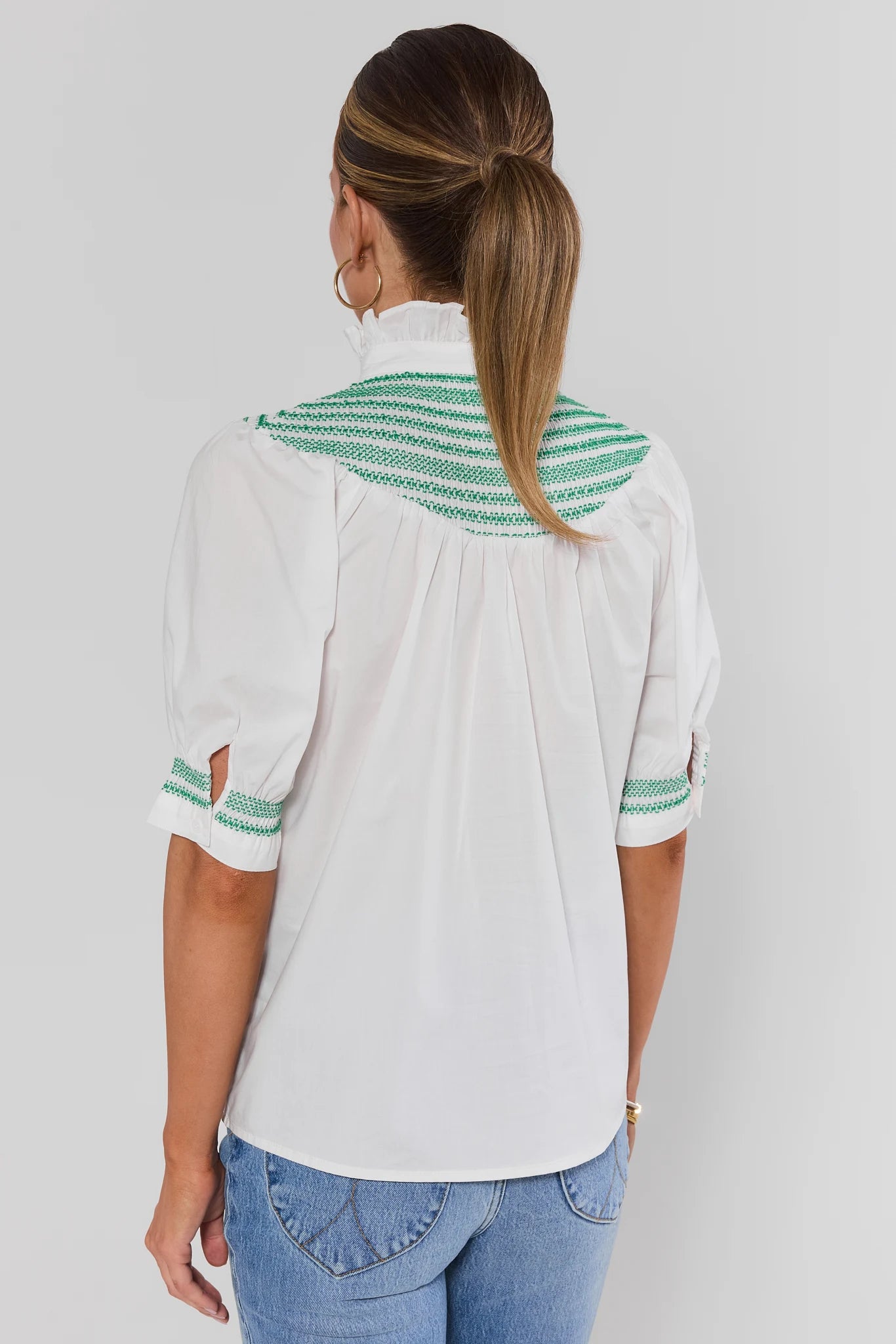 Woman wearing Yvonne White and Green Embroidered Top on a white background turned