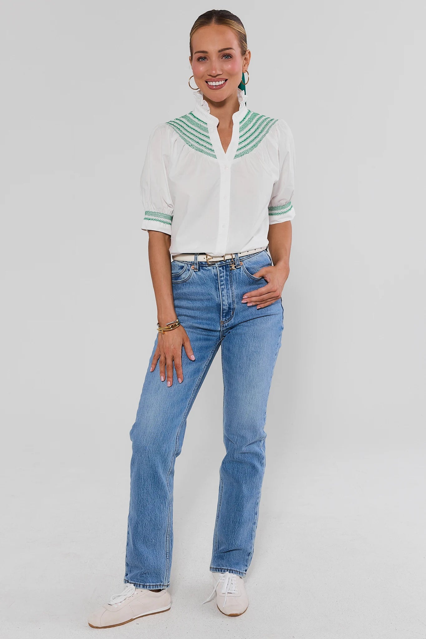 Woman wearing Yvonne White and Green Embroidered Top and jeans on a white background