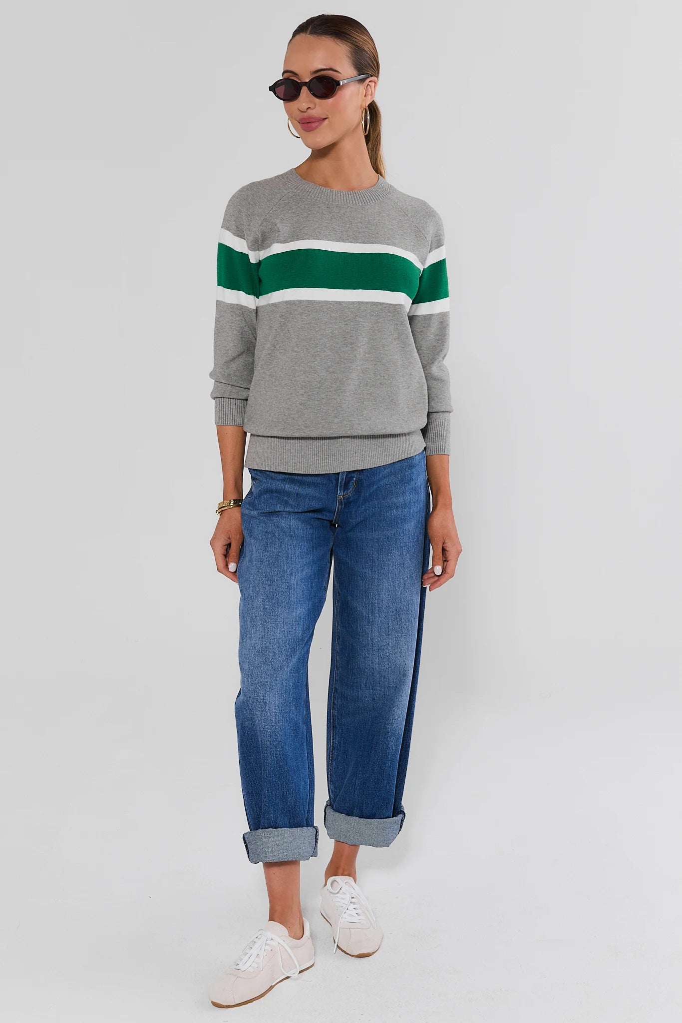 Woman wearing Dylan Green Stripe Sweater and jeans on a white background