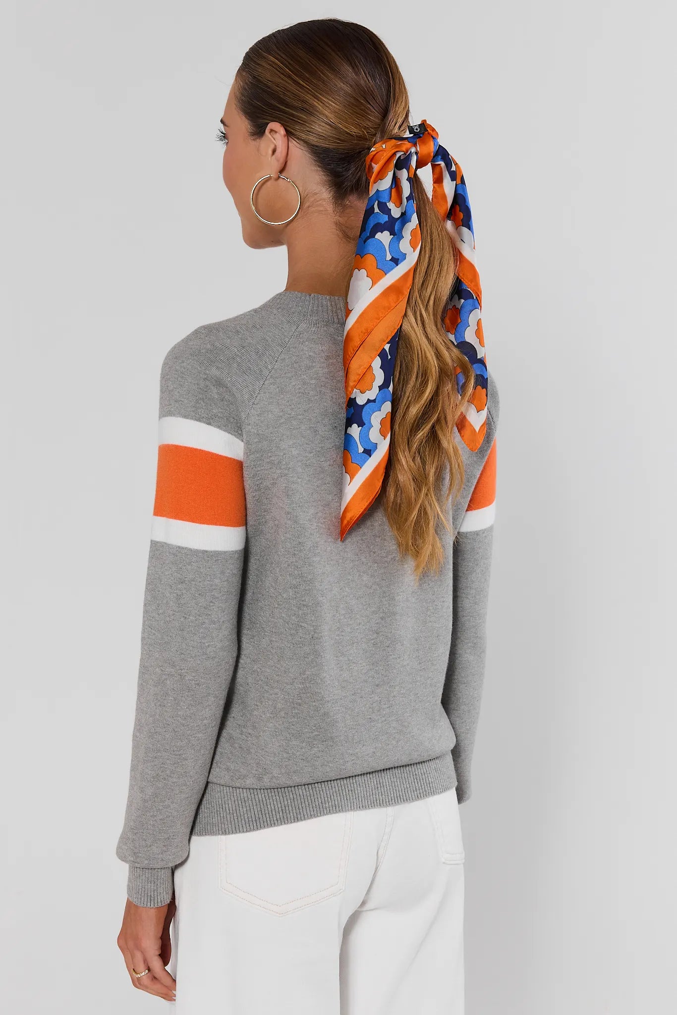 Woman wearing Dylan Orange Stripe Sweater on a white background standing