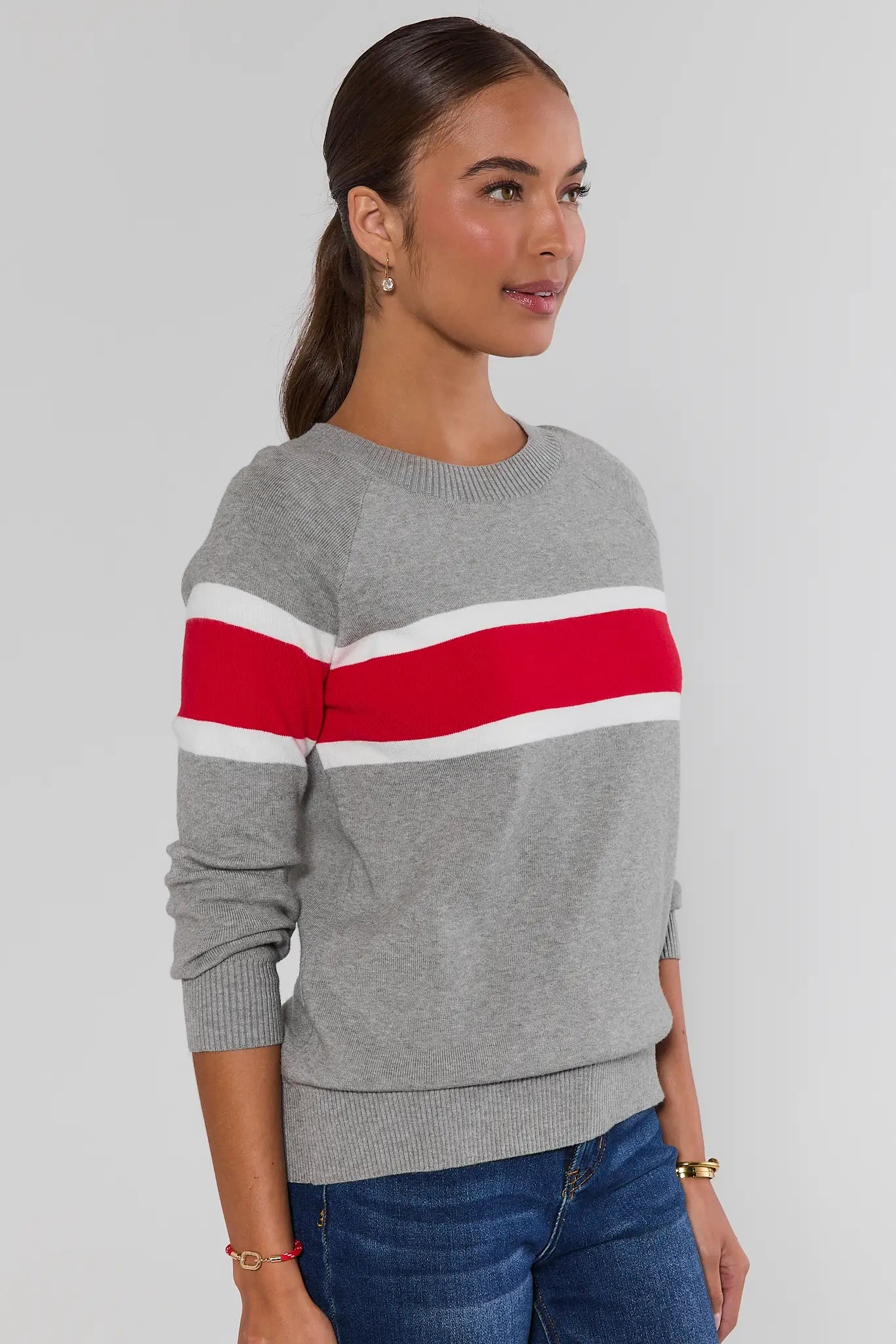 Woman wearing Dylan Red Stripe Sweater and dark jeans on a white background