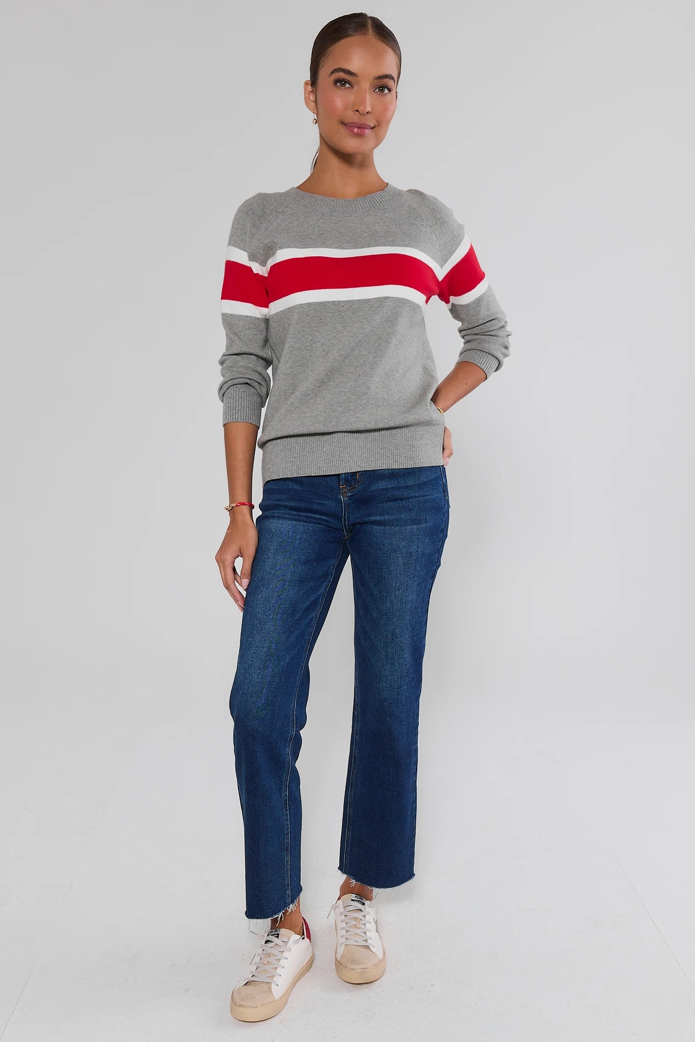 Woman wearing Dylan Red Stripe Sweater and jeans on a white background