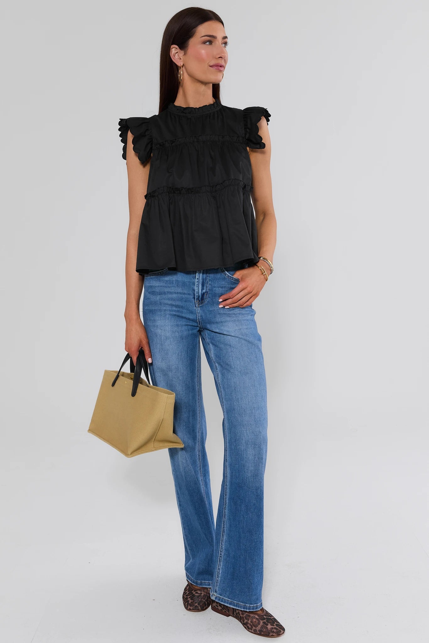 woman standing wearing Black Tiered Flutter Sleeve Top and jeans on a white background