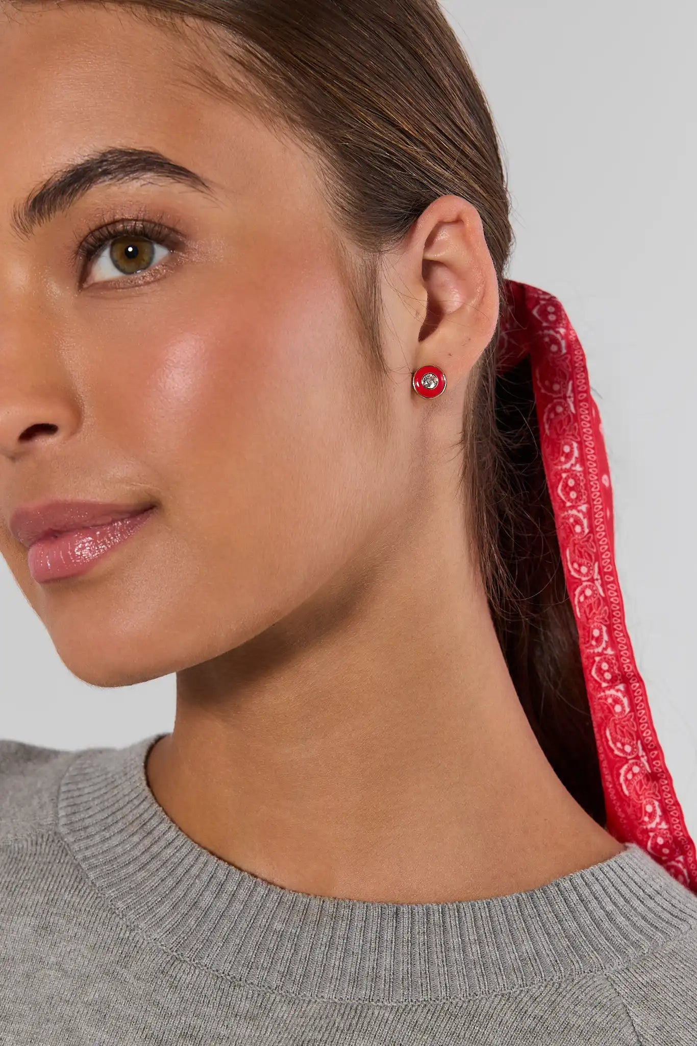 a woman wearing red enamel rhinestone earrings
