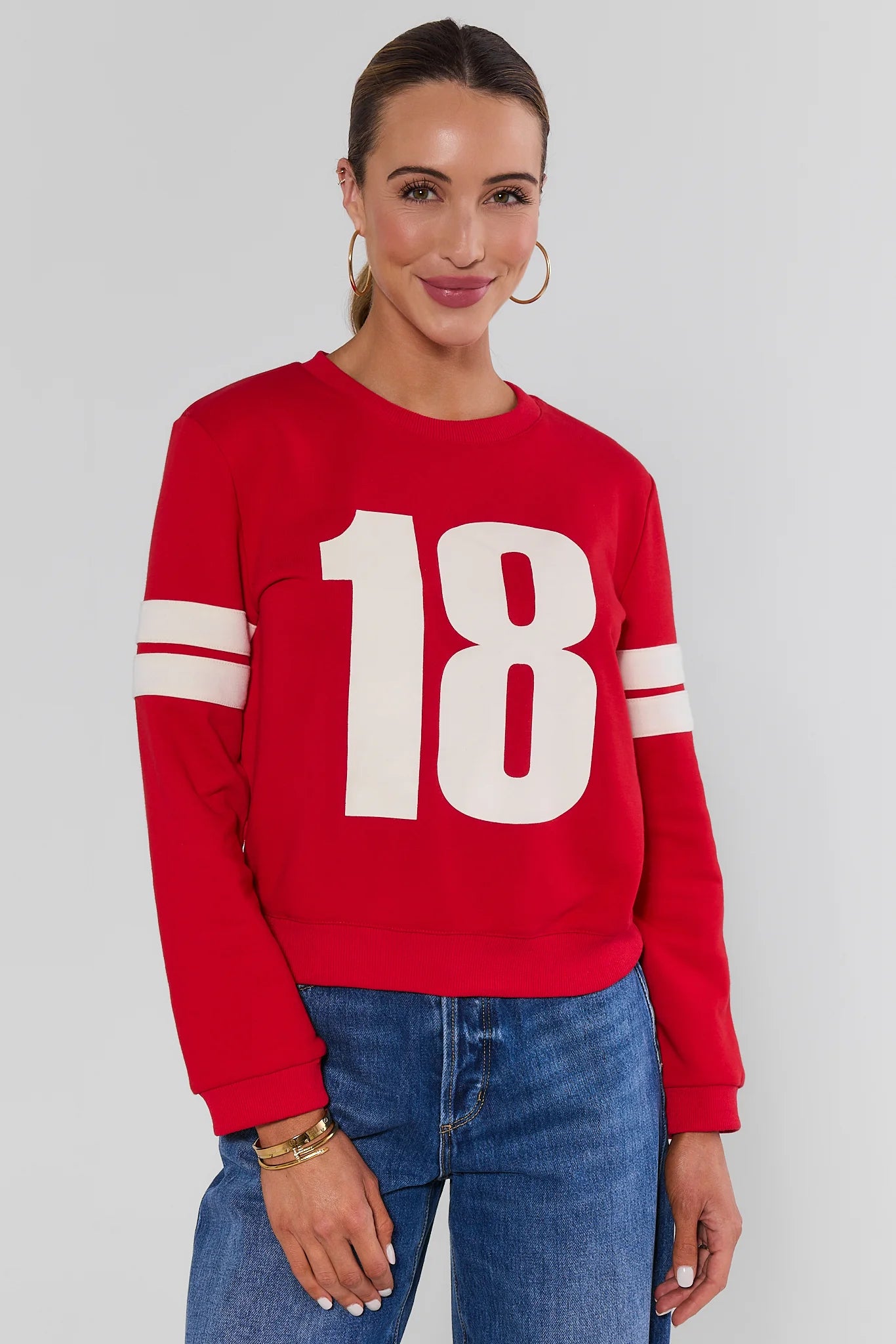 Woman wearing Red Varsity Number Pullover with jeans on a white background