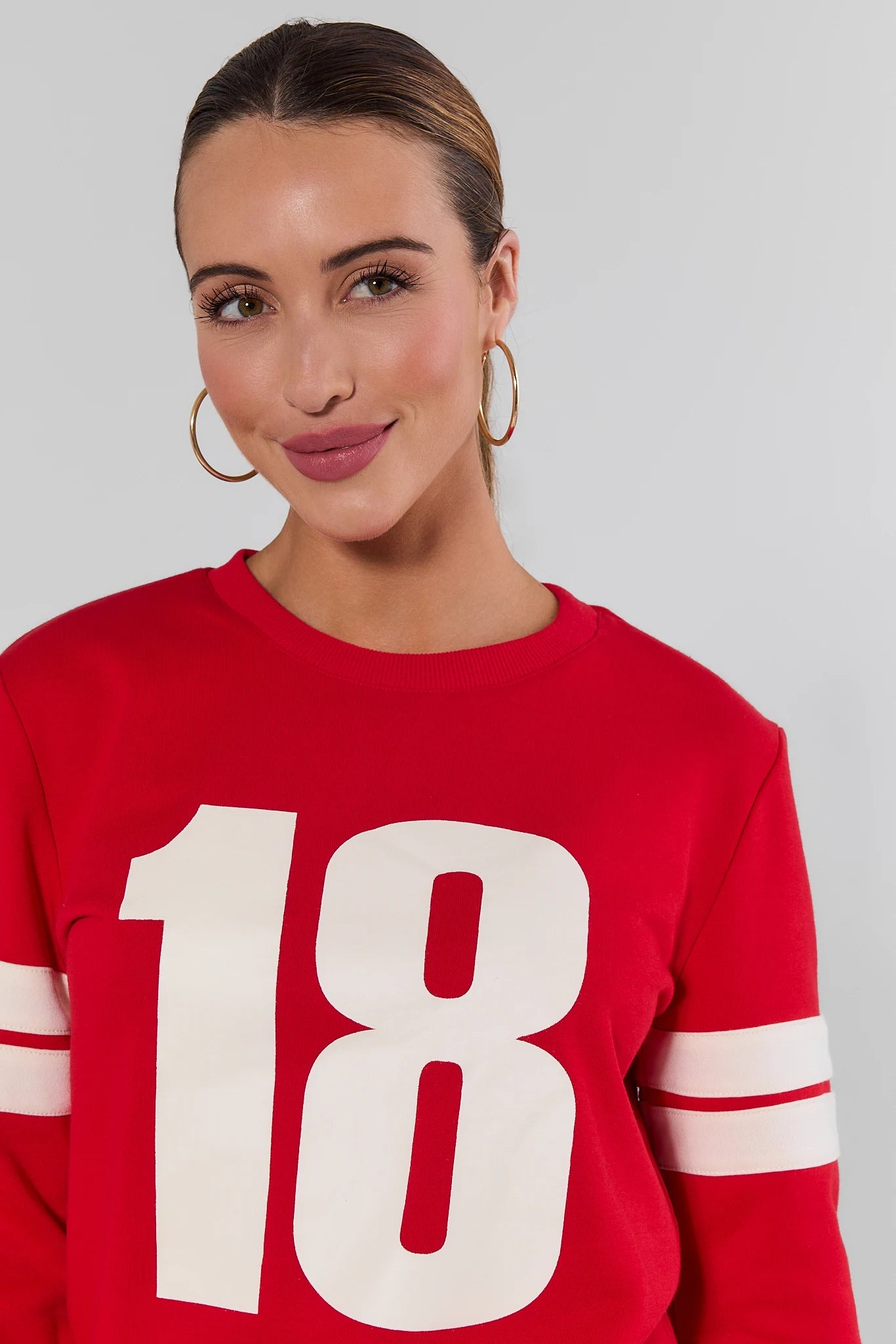 close up Woman wearing Red Varsity Number Pullover with jeans on a white background
