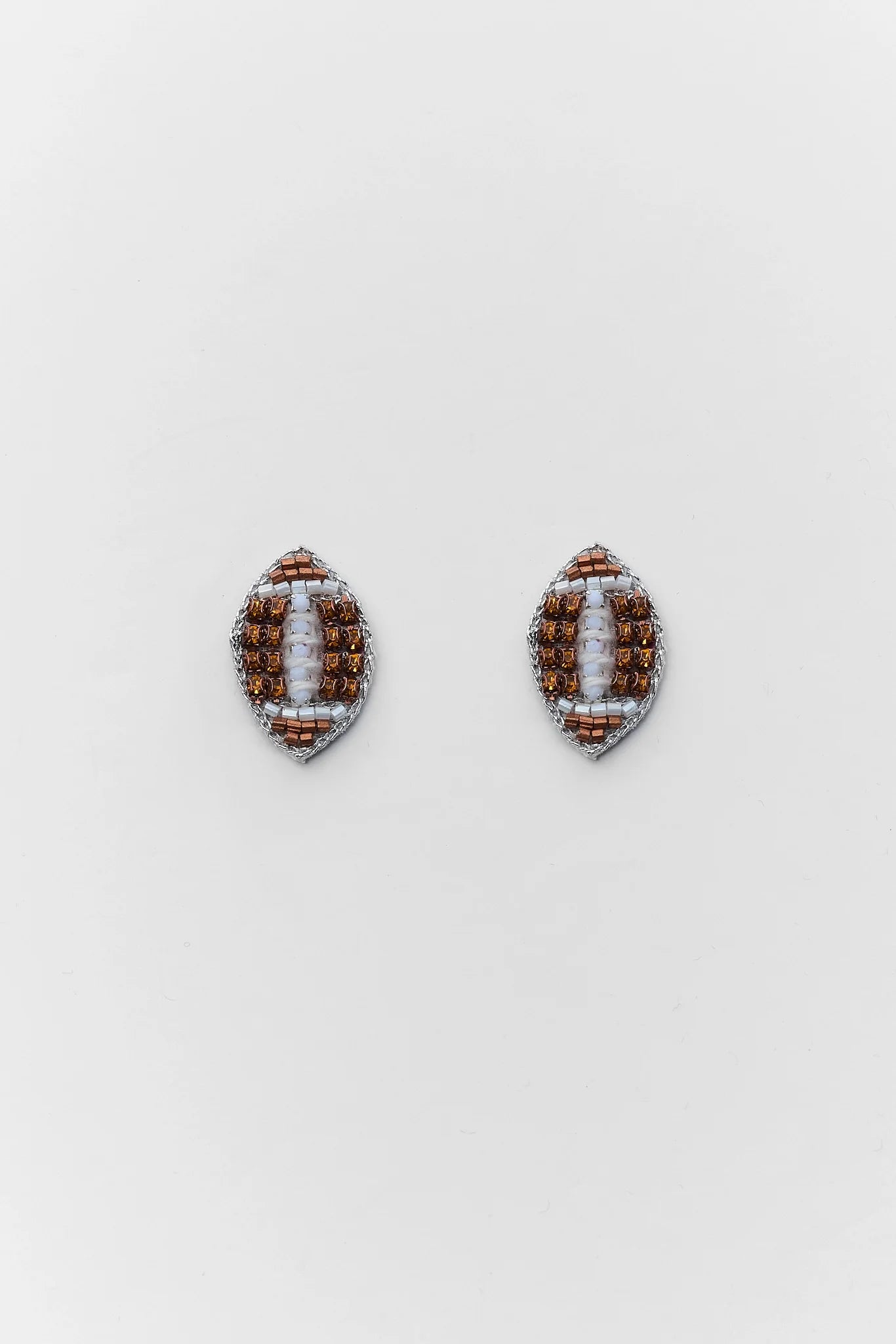 A pair of football-shaped stud earrings made from brown and white seed beads, displayed on a clean white background.