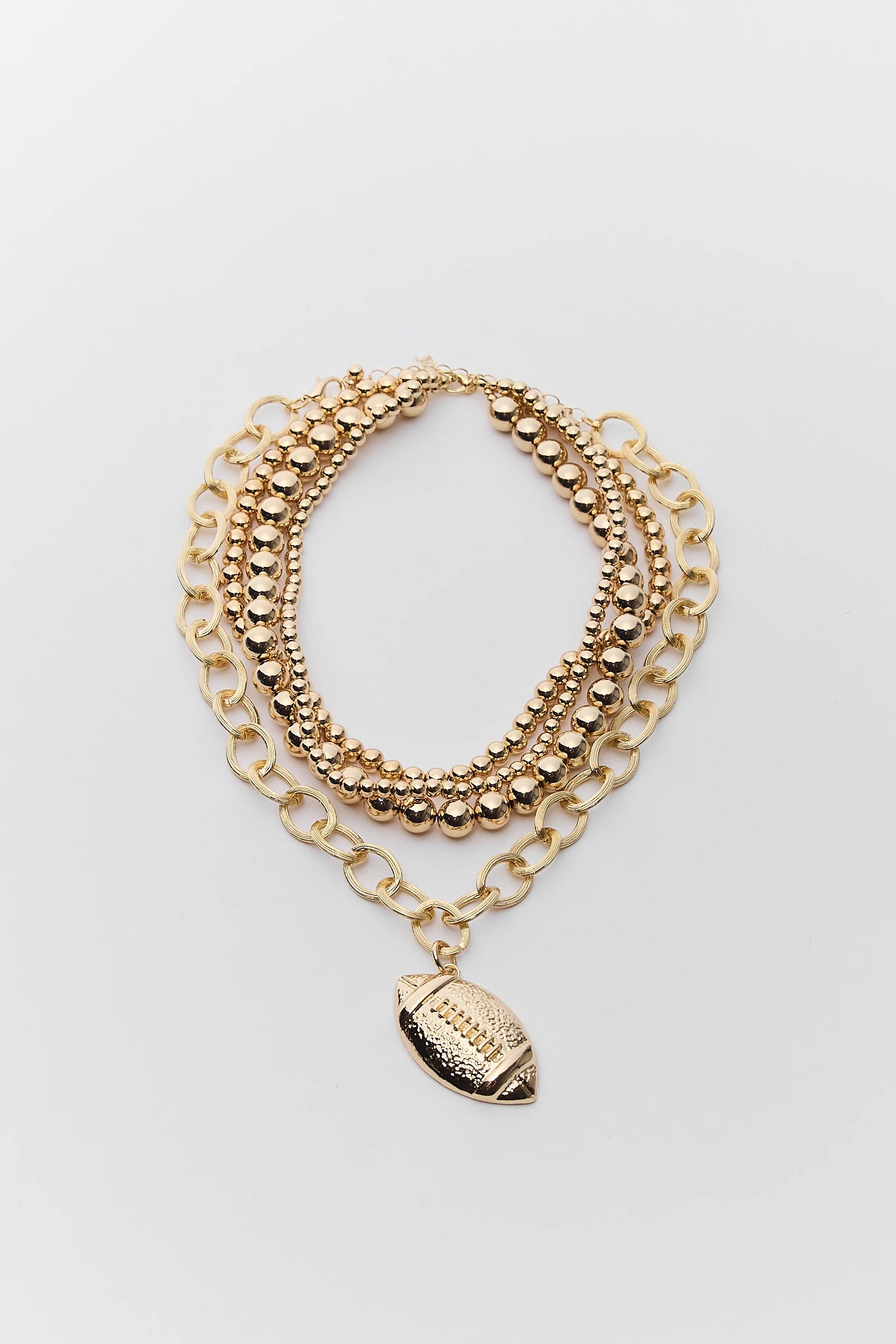 A gold-toned multi-strand chain necklace featuring a football-shaped charm, displayed on a light gray background.