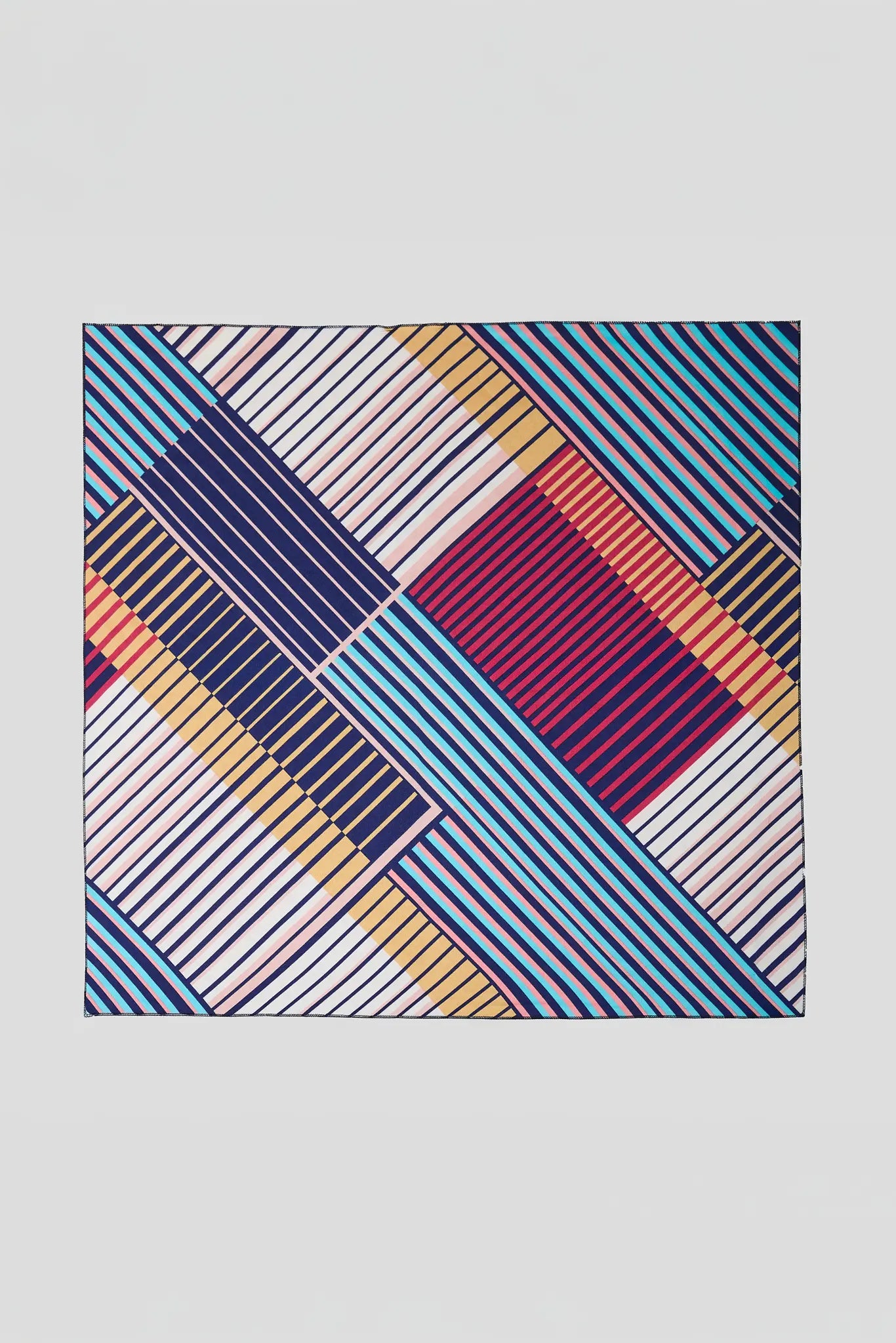A square scarf featuring a complex geometric pattern of diagonal stripes and blocks in blue, navy, burgundy, orange, and beige on a light gray background.