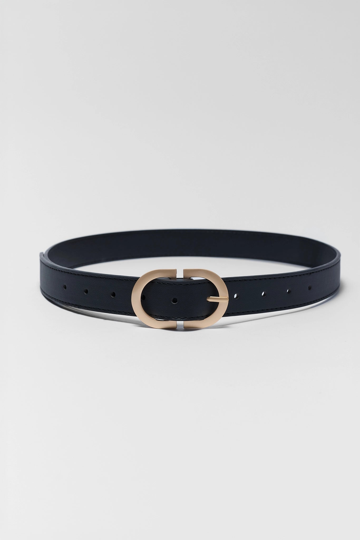 A slim black leather belt with a polished gold-tone oval buckle, displayed horizontally on a clean, light gray background.