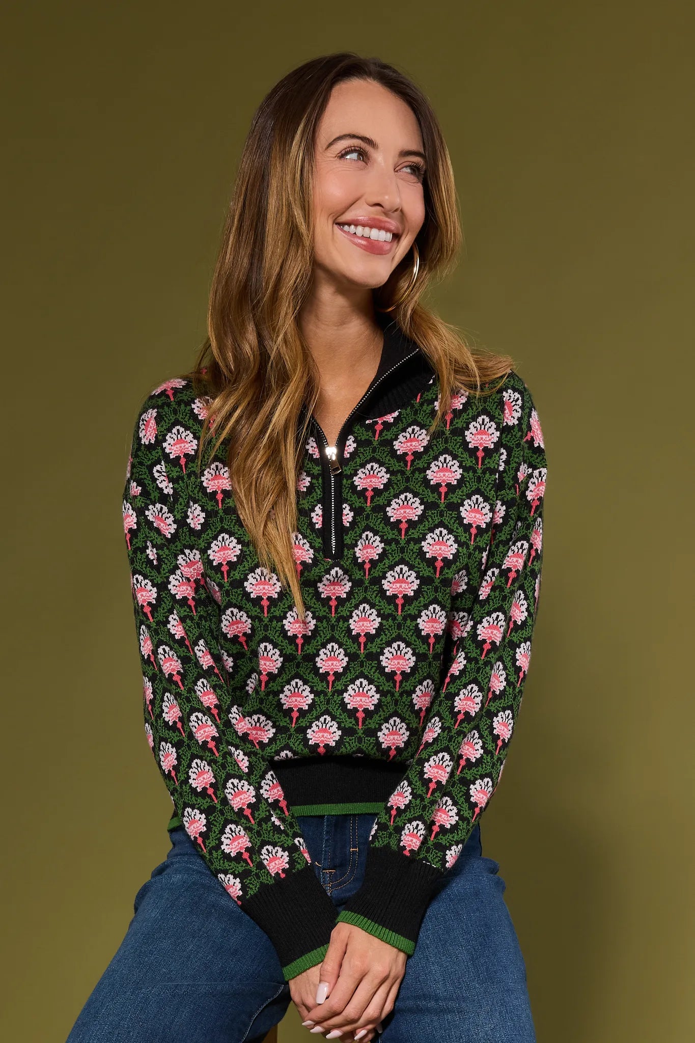Woman wearing a floral patterned Janie Sweater against a green background