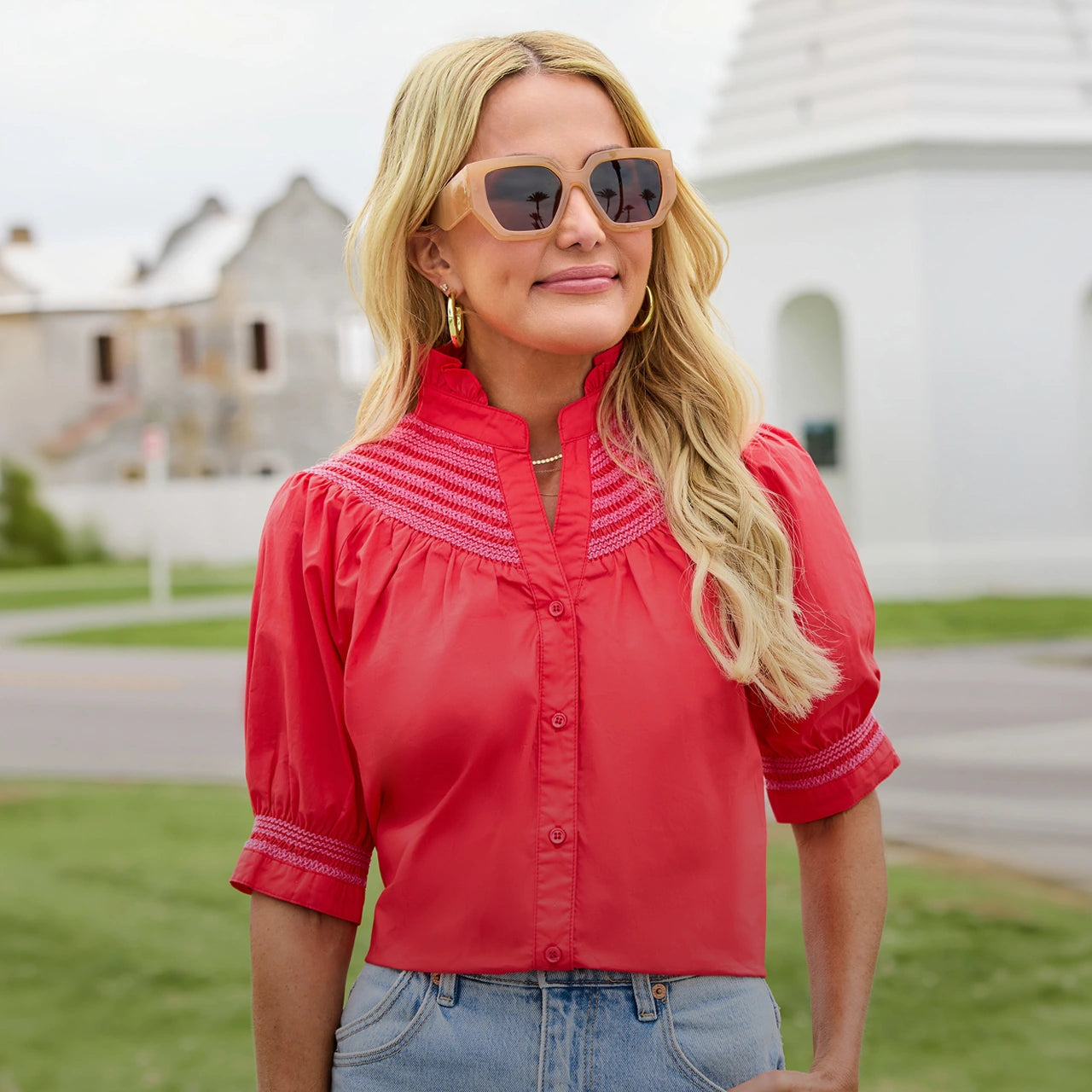 Woman wearing a red blouse with white trim and sunglasses outdoors. desktop