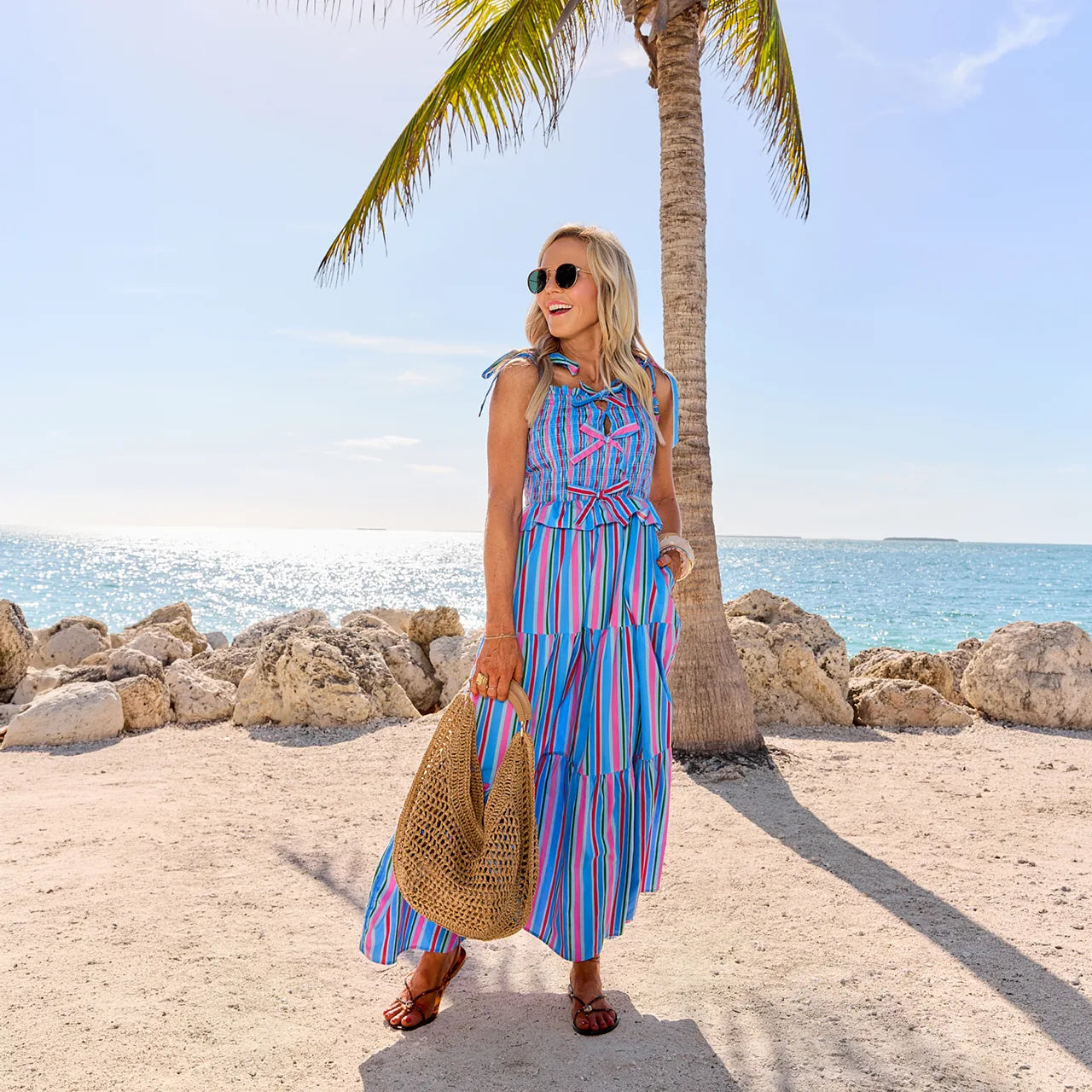 Woman in a colorful dress standing on a beach with palm trees and ocean in the background desktop