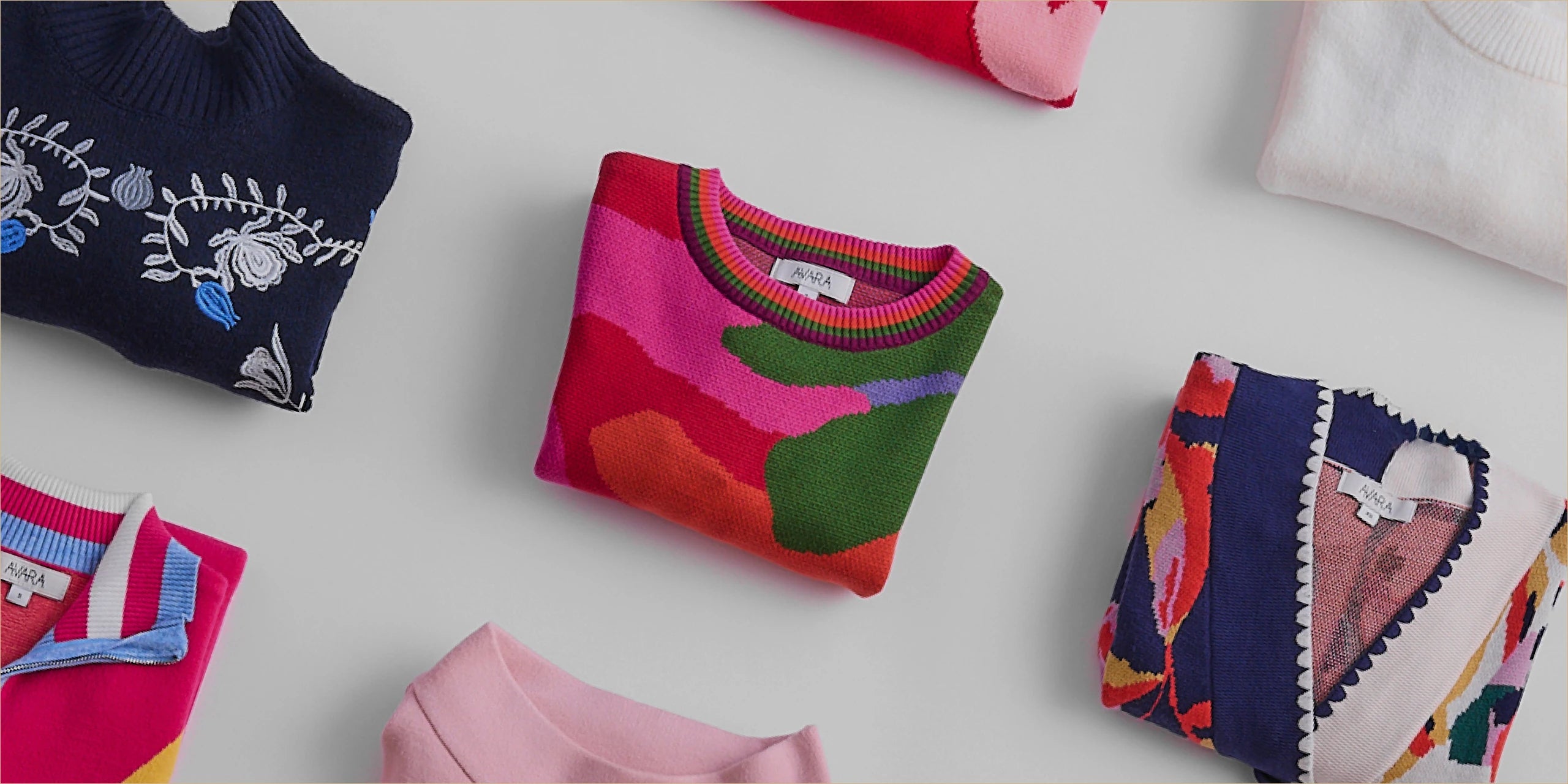 Colorful sweaters on a light gray surface