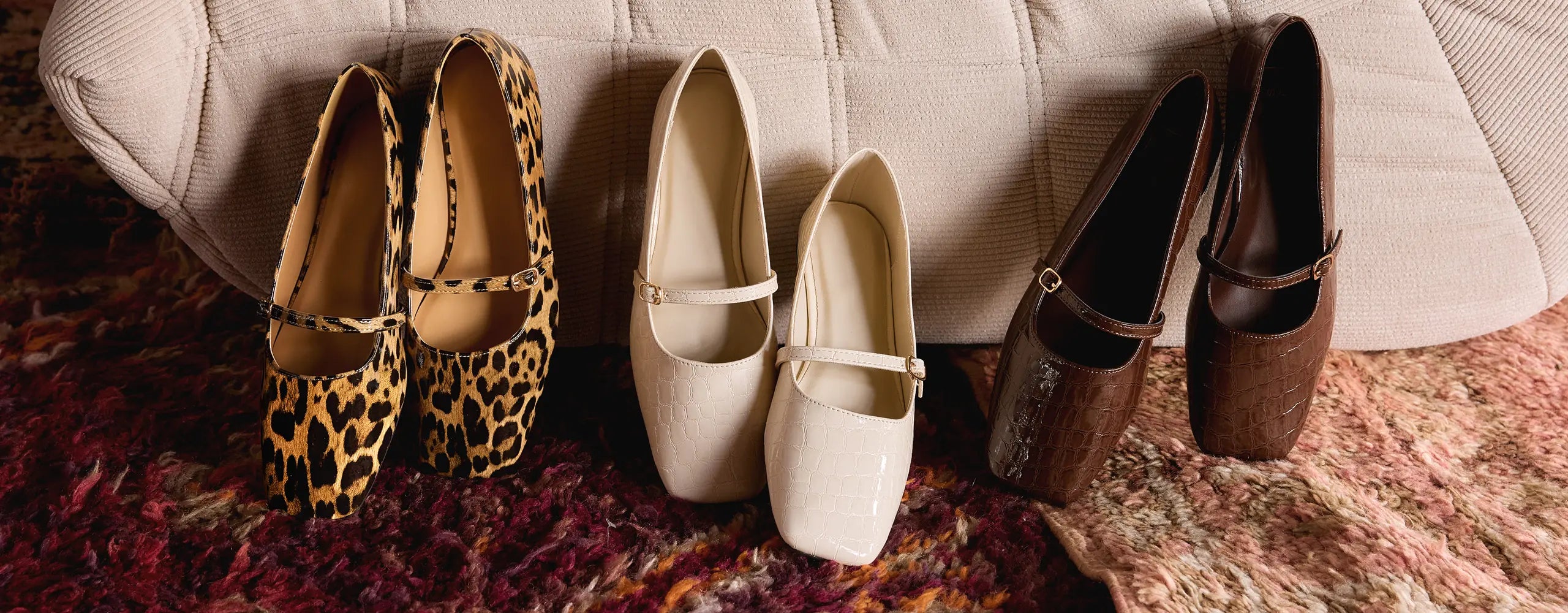 Four pairs of shoes arranged on a textured surface with a neutral background