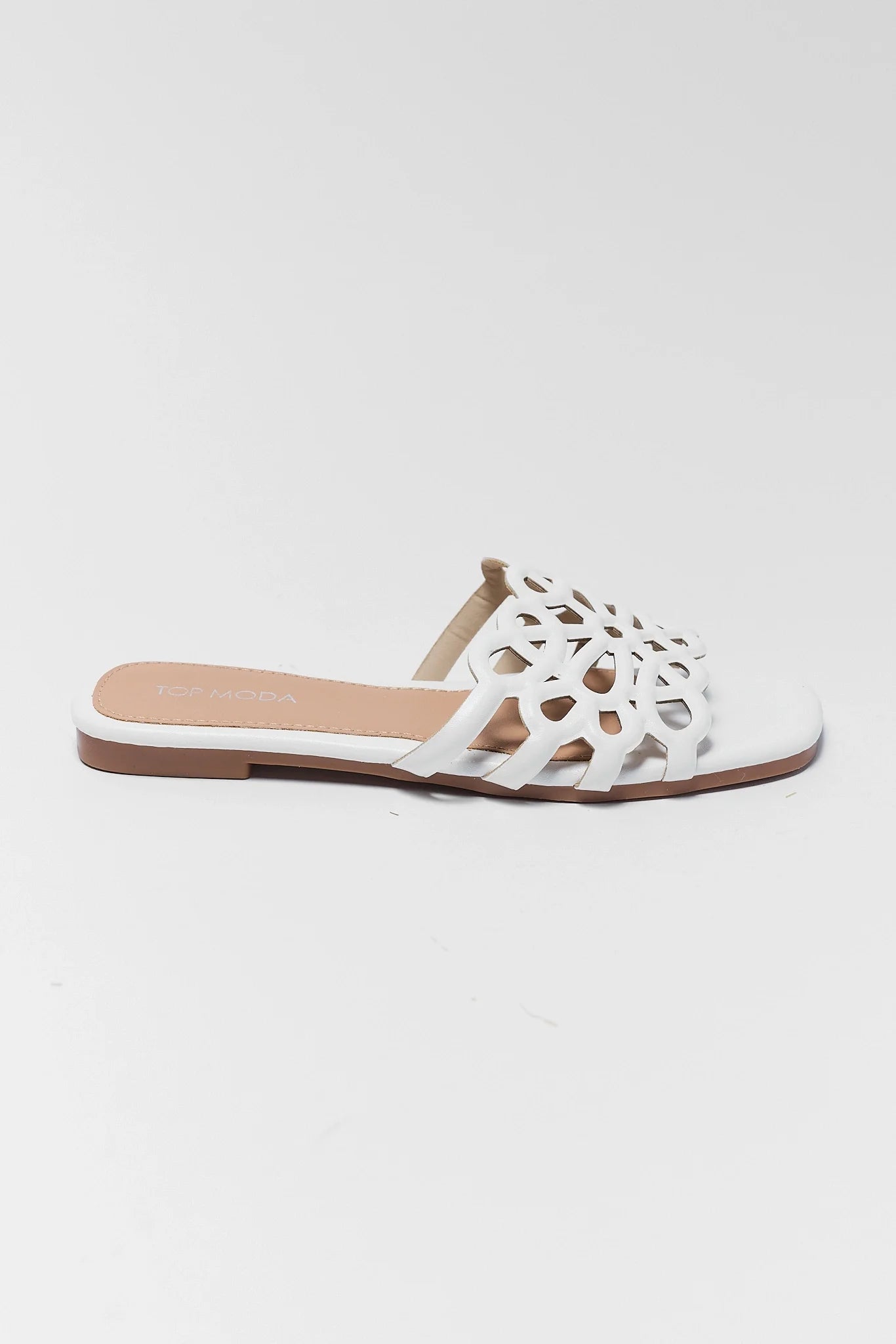 White sandal with cut-out design on a light gray background