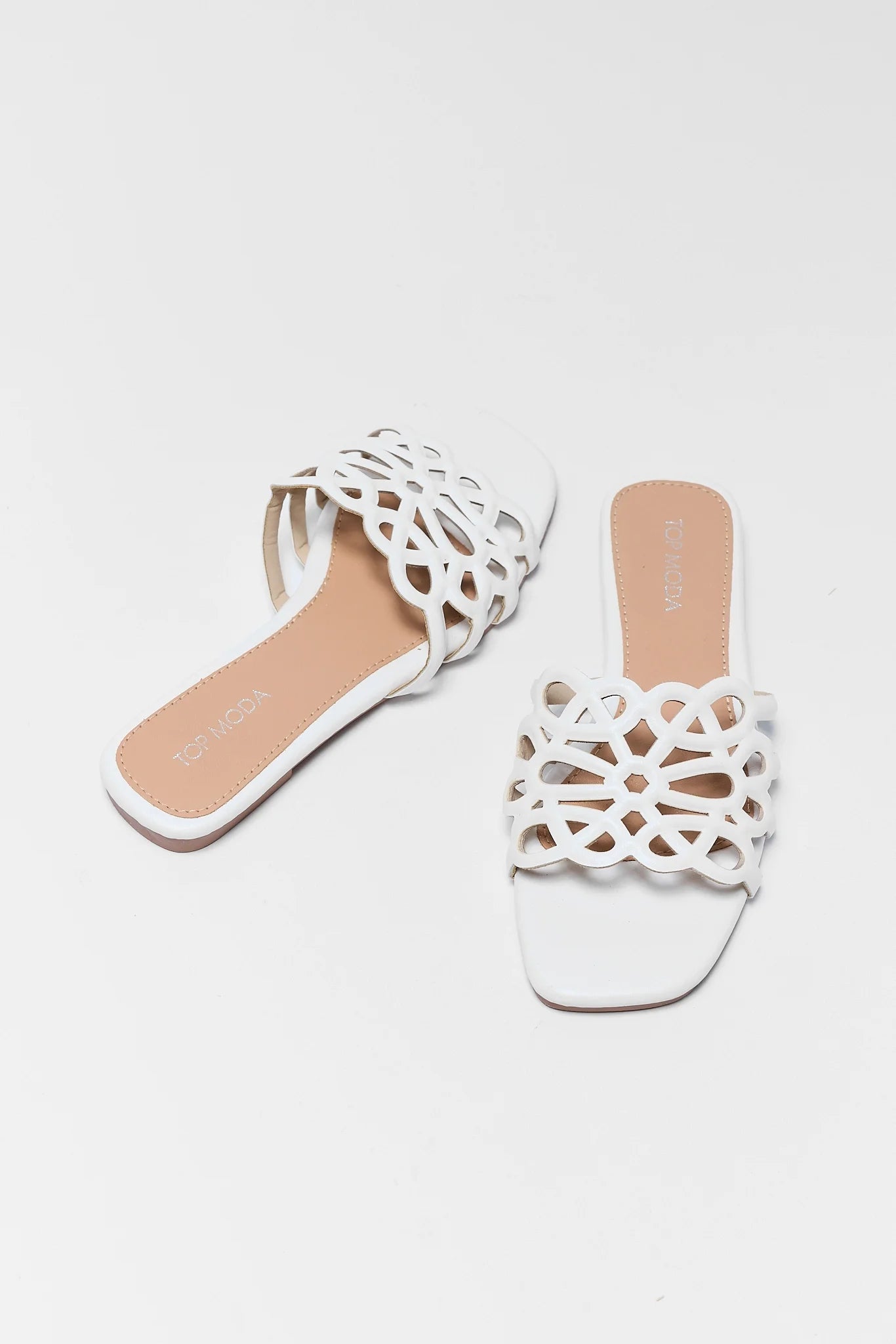 White sandals with intricate cut-out design on a white background