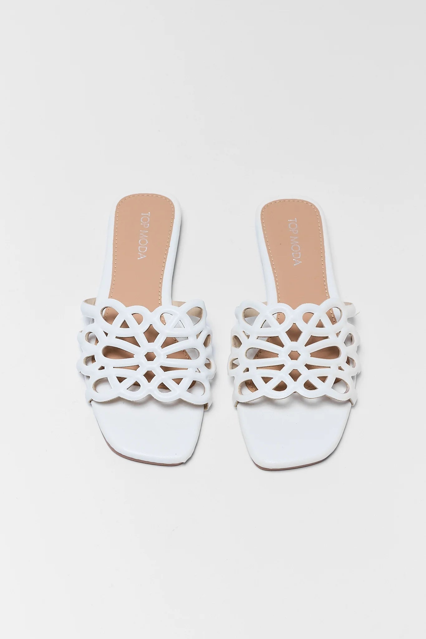 White sandals with decorative cut-out design on a light background
