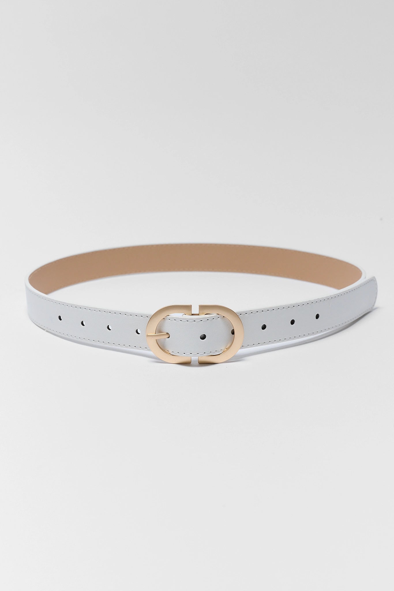 A slim white faux leather belt with a gold-tone interlocking O-ring buckle, displayed against a light gray studio background.
