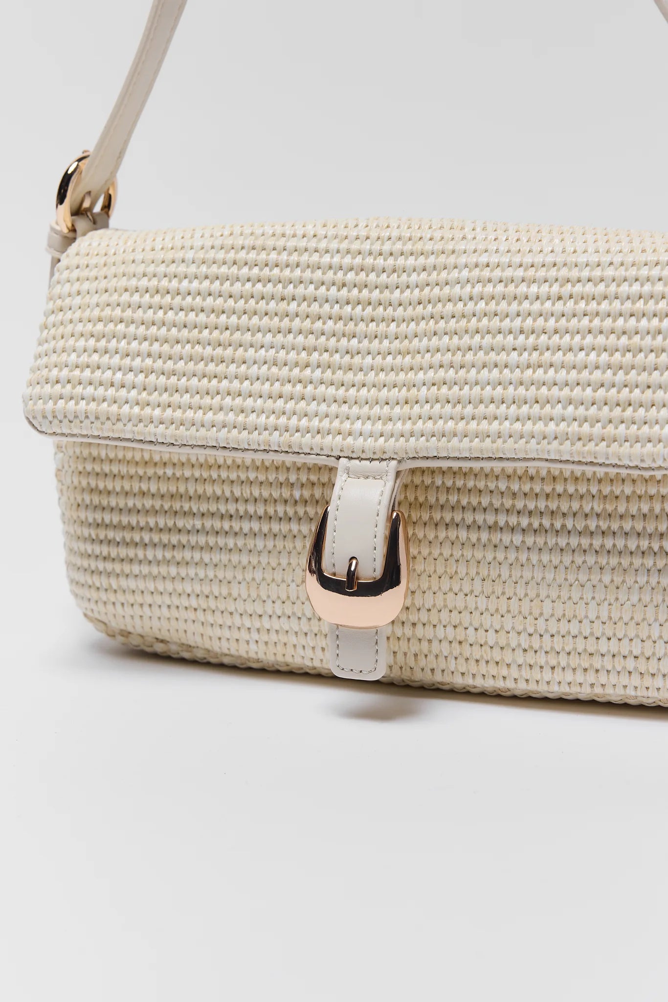 close up Beige woven handbag with a strap on a light gray background