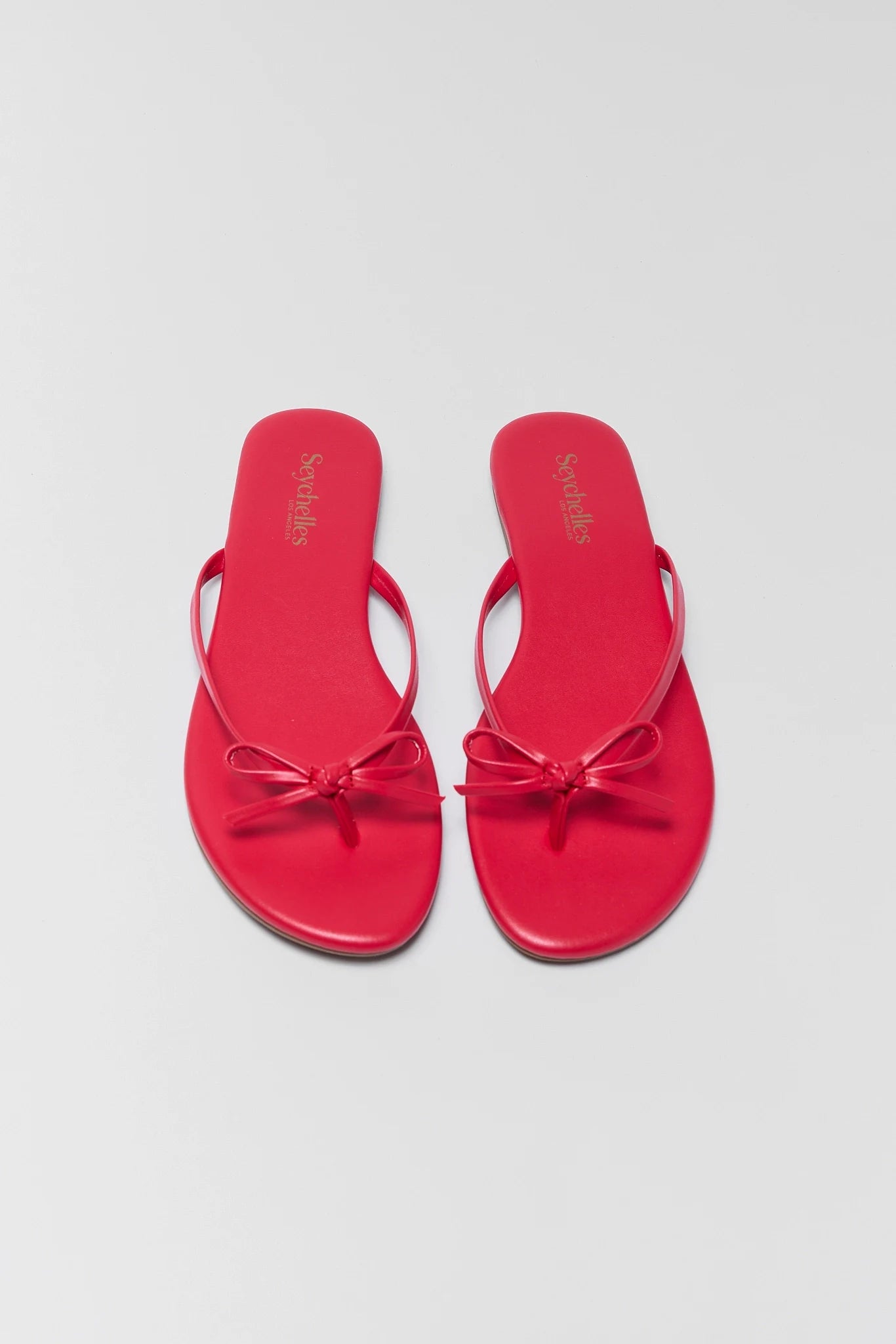 Red sandals with a bow on a light gray background two