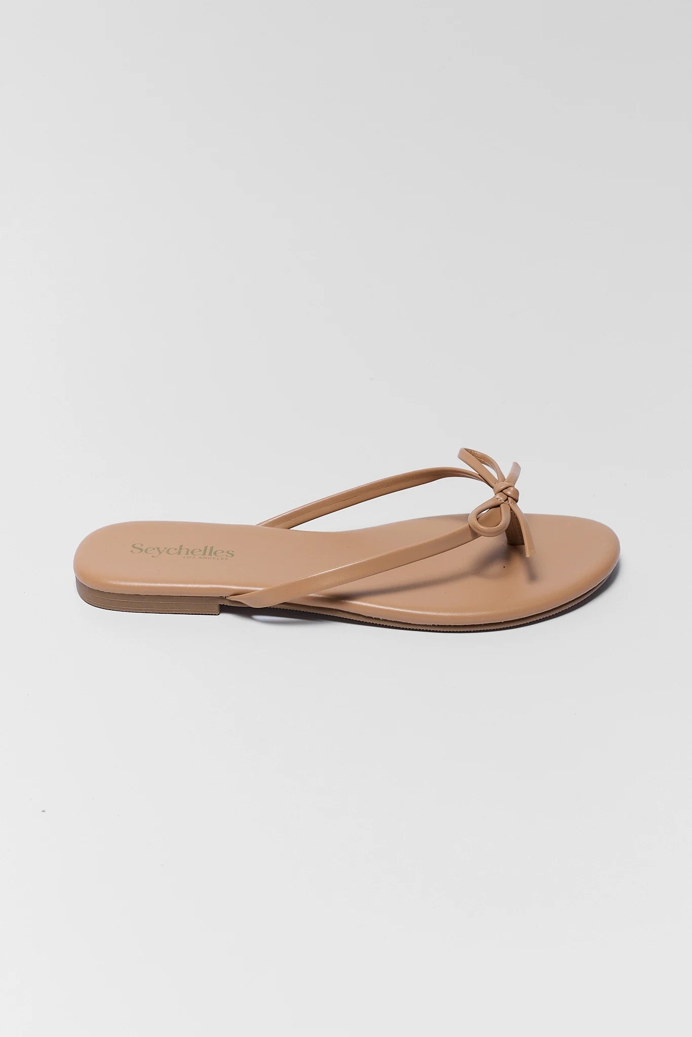 one Beige sandal with a bow on a light gray background