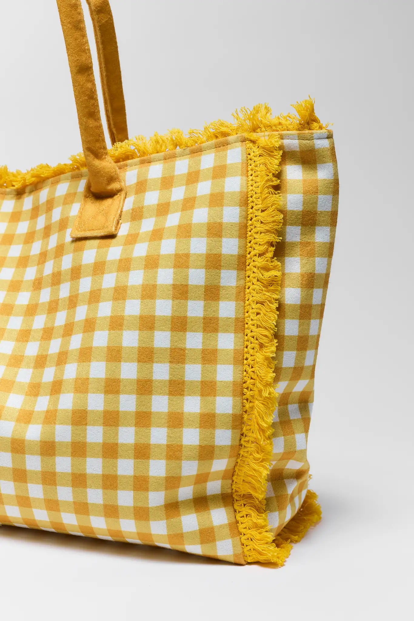 close up Yellow and white checkered bag with frayed edges on a light gray background