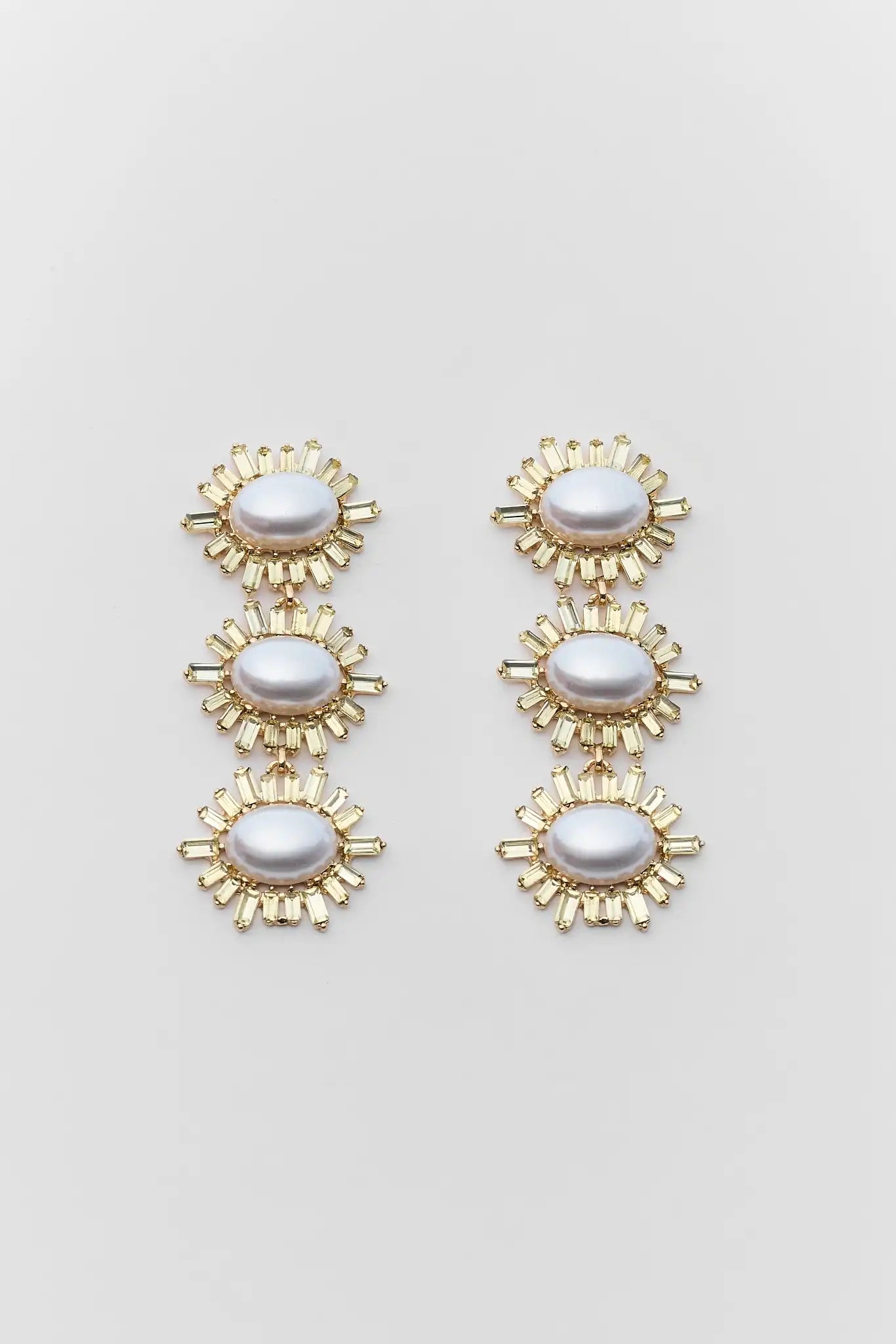 Pair of gold and pearl earrings on a light gray background
