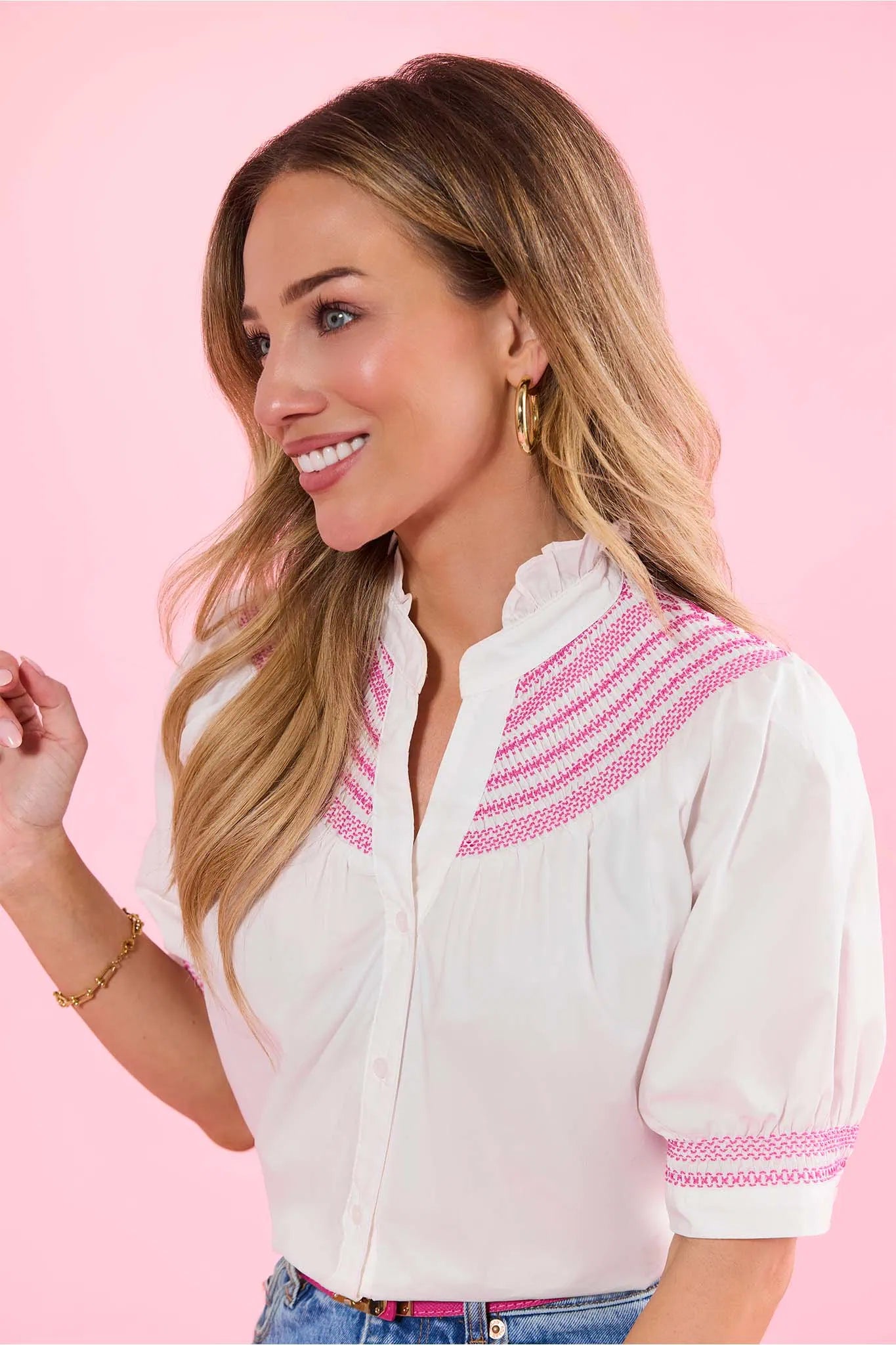 Woman wearing a white blouse with pink accents on a pink background