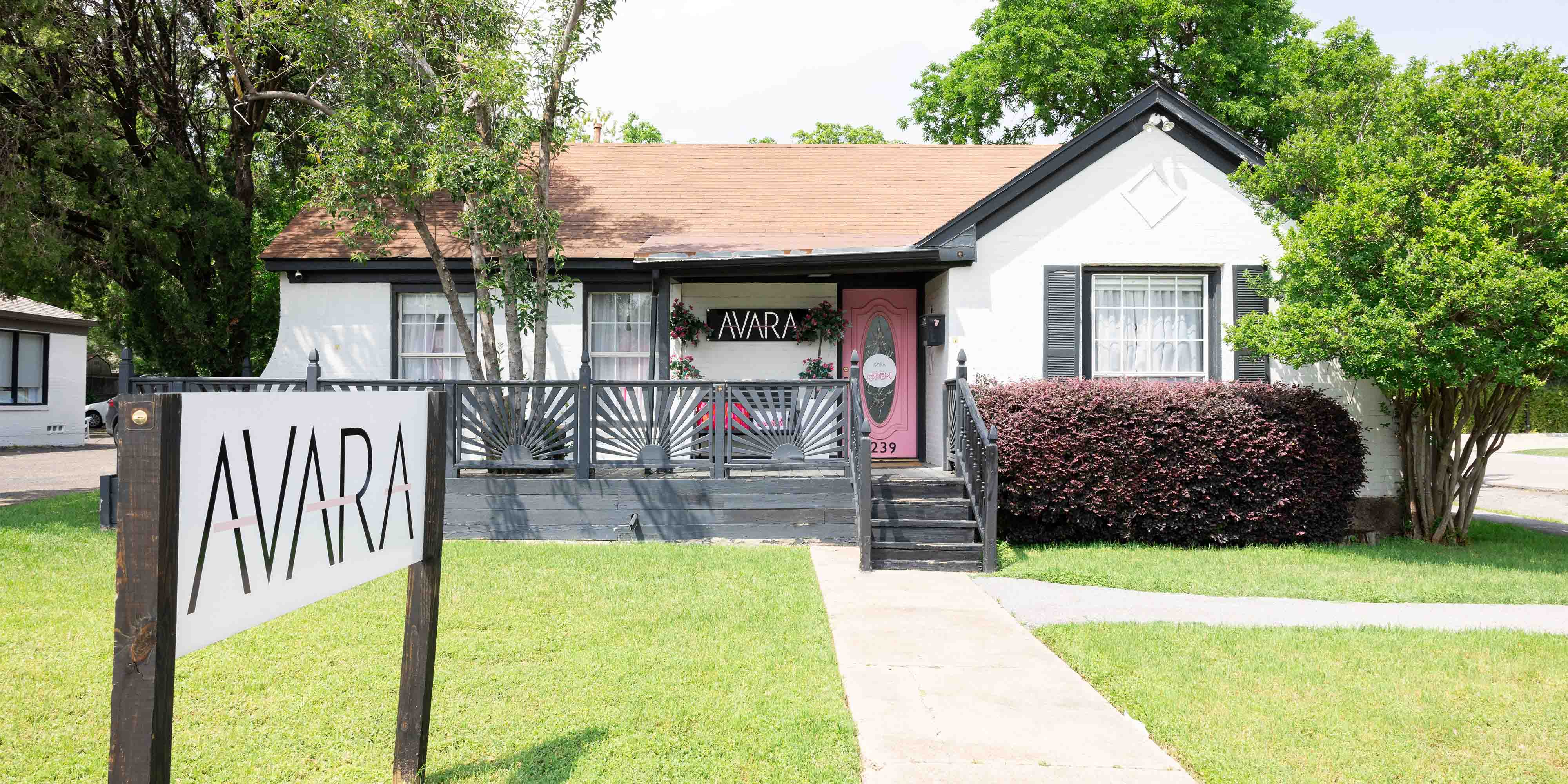 white building with sign and green grass and trees
