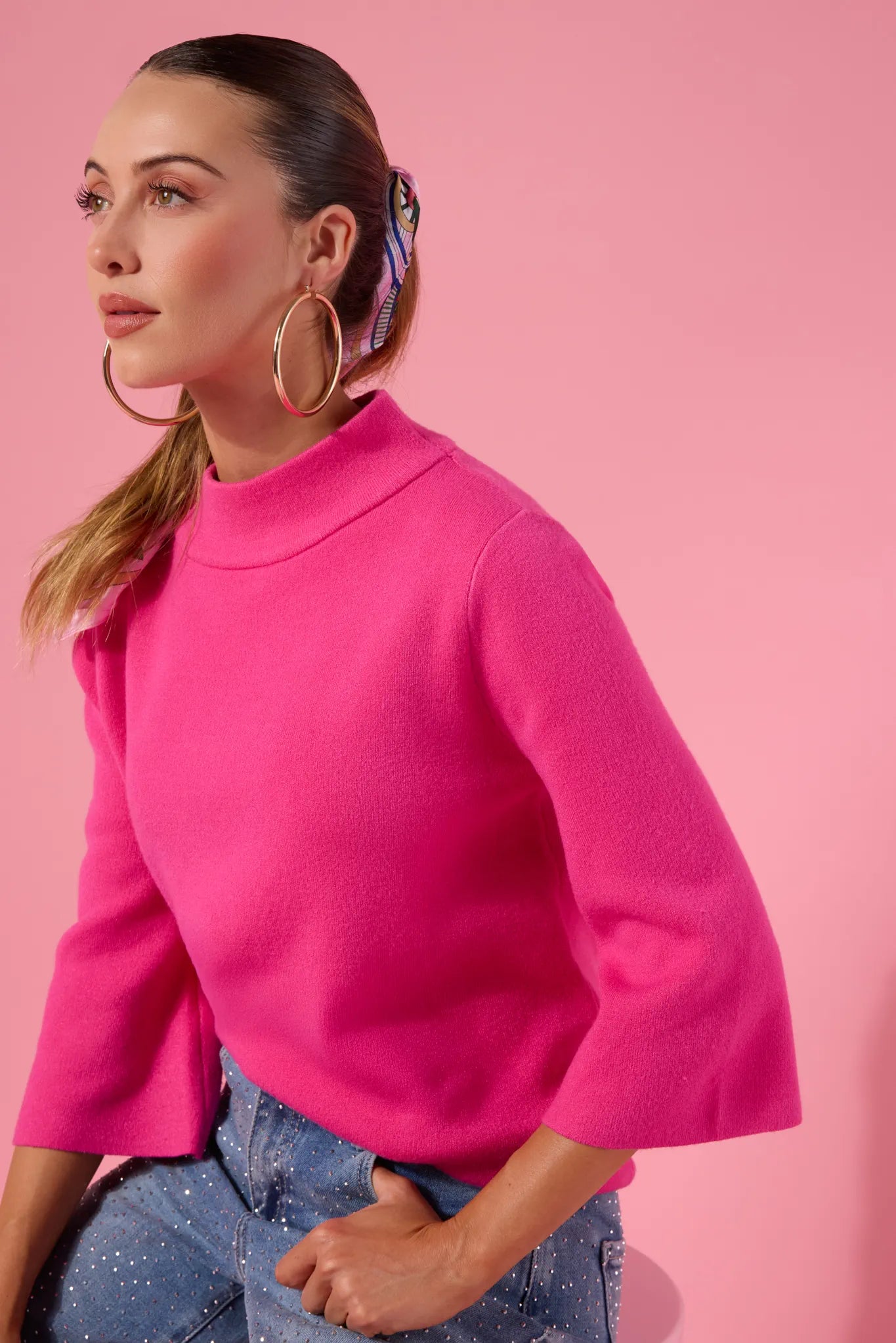 Woman wearing a bright pink jackie sweater against a pink background