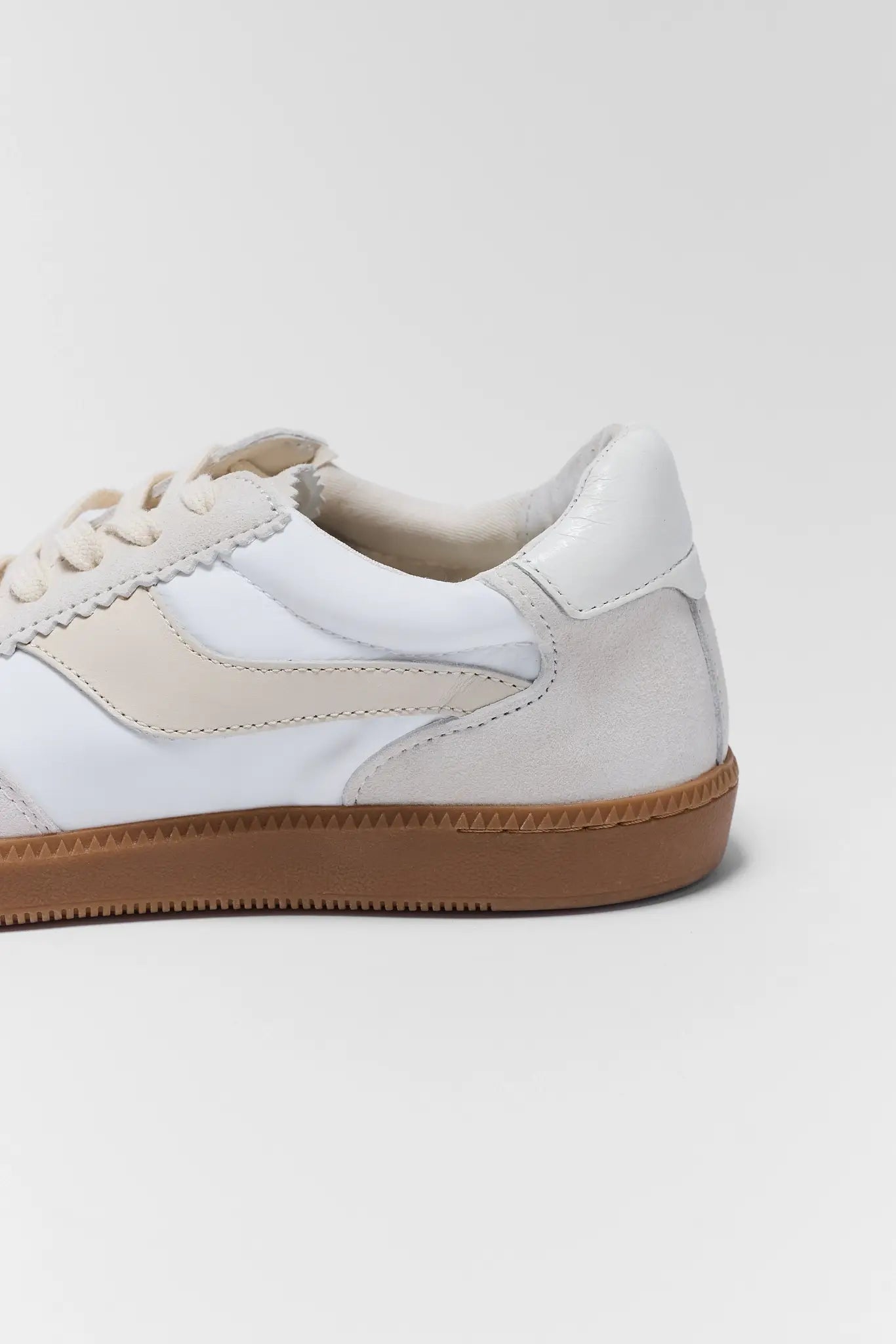 White sneaker with beige accents on a light gray background