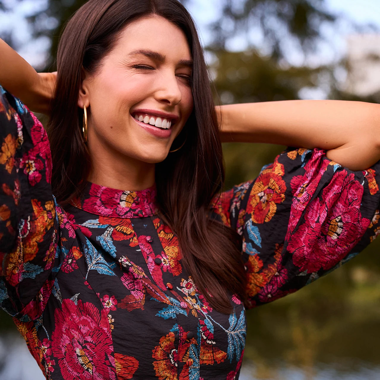 Woman wearing a colorful floral dress with a blurred natural background