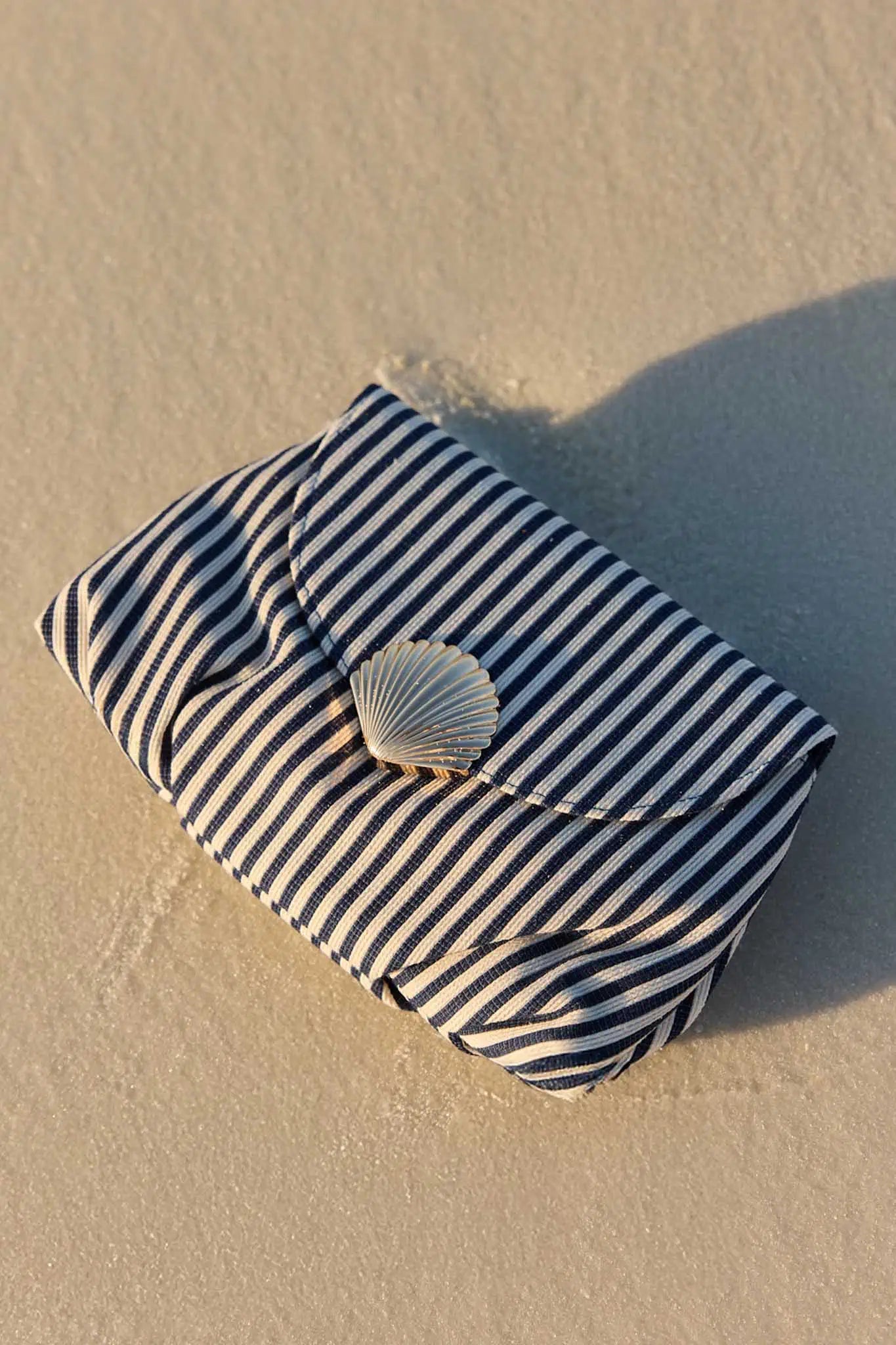 Striped pouch with a shell on a sandy surface