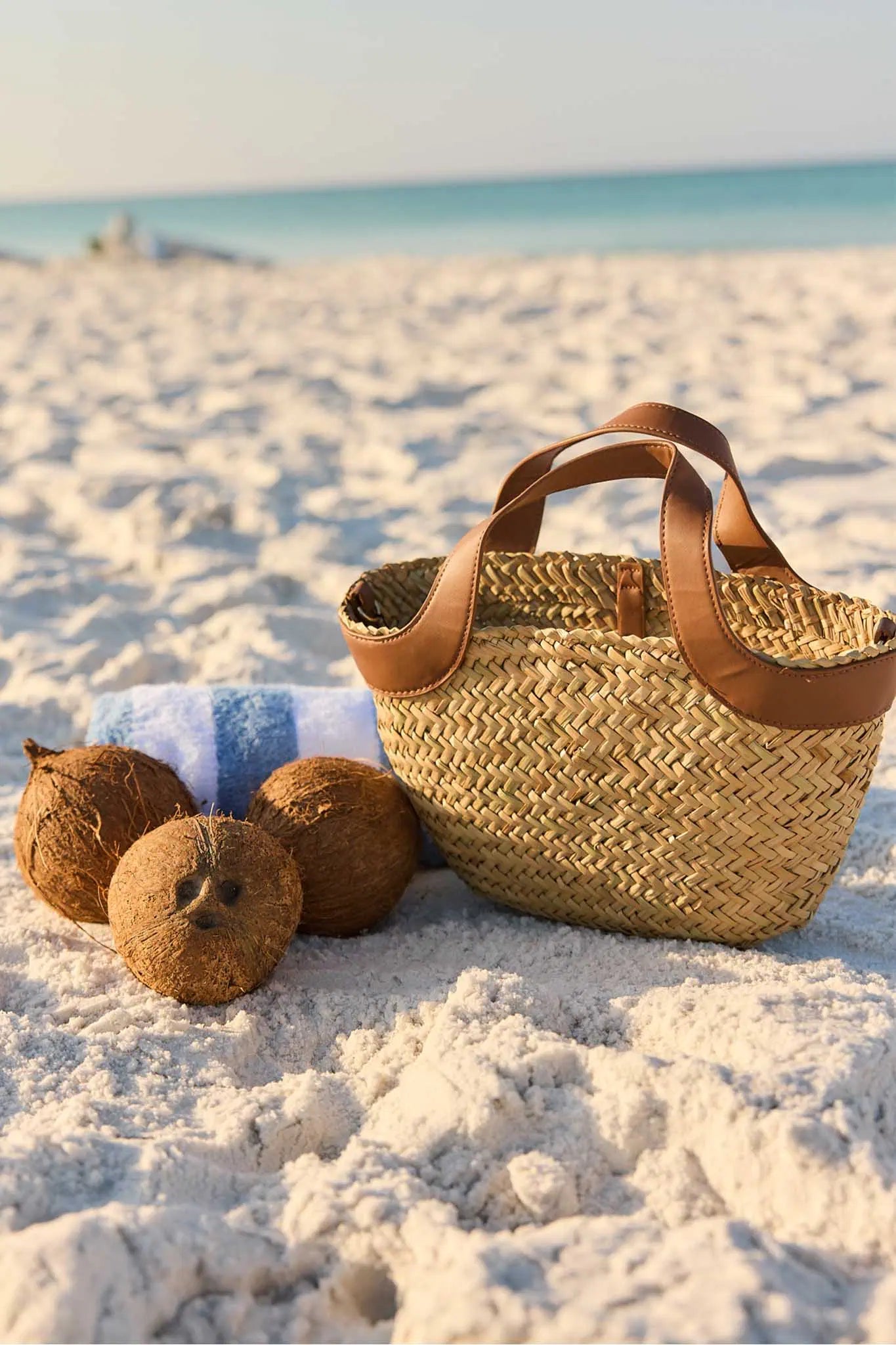 Woven basket with coconuts on a sandy beach