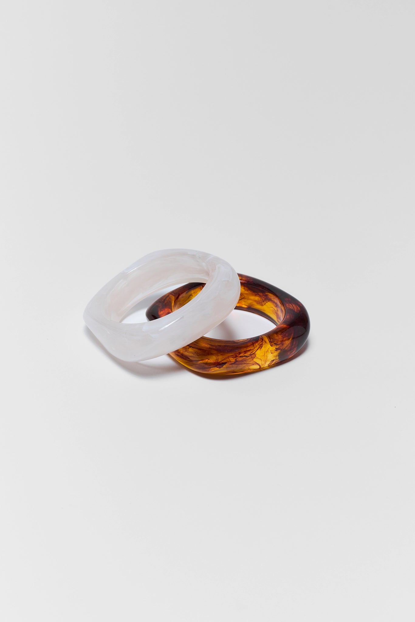 Two rings, one white and one brown, on a light gray background