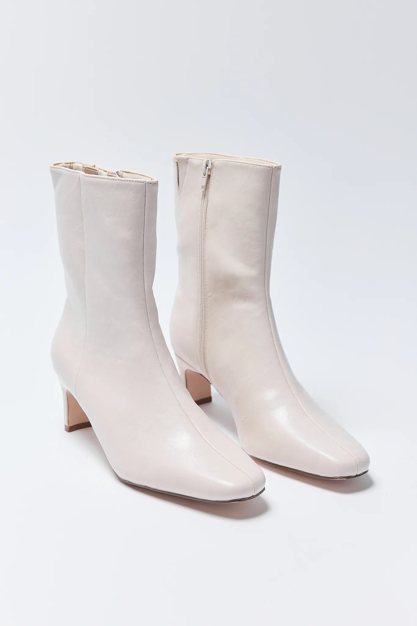 Pair of white ankle Adler Boots on a light gray background