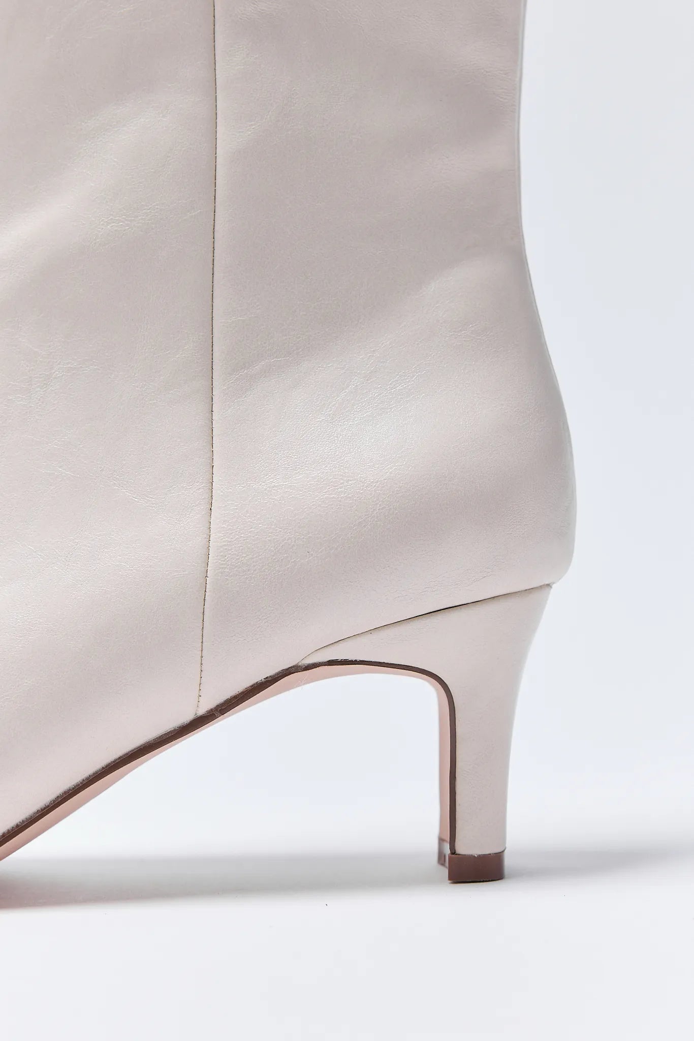 Close-up of a white ankle Adler Boots with a thin heel on a white background