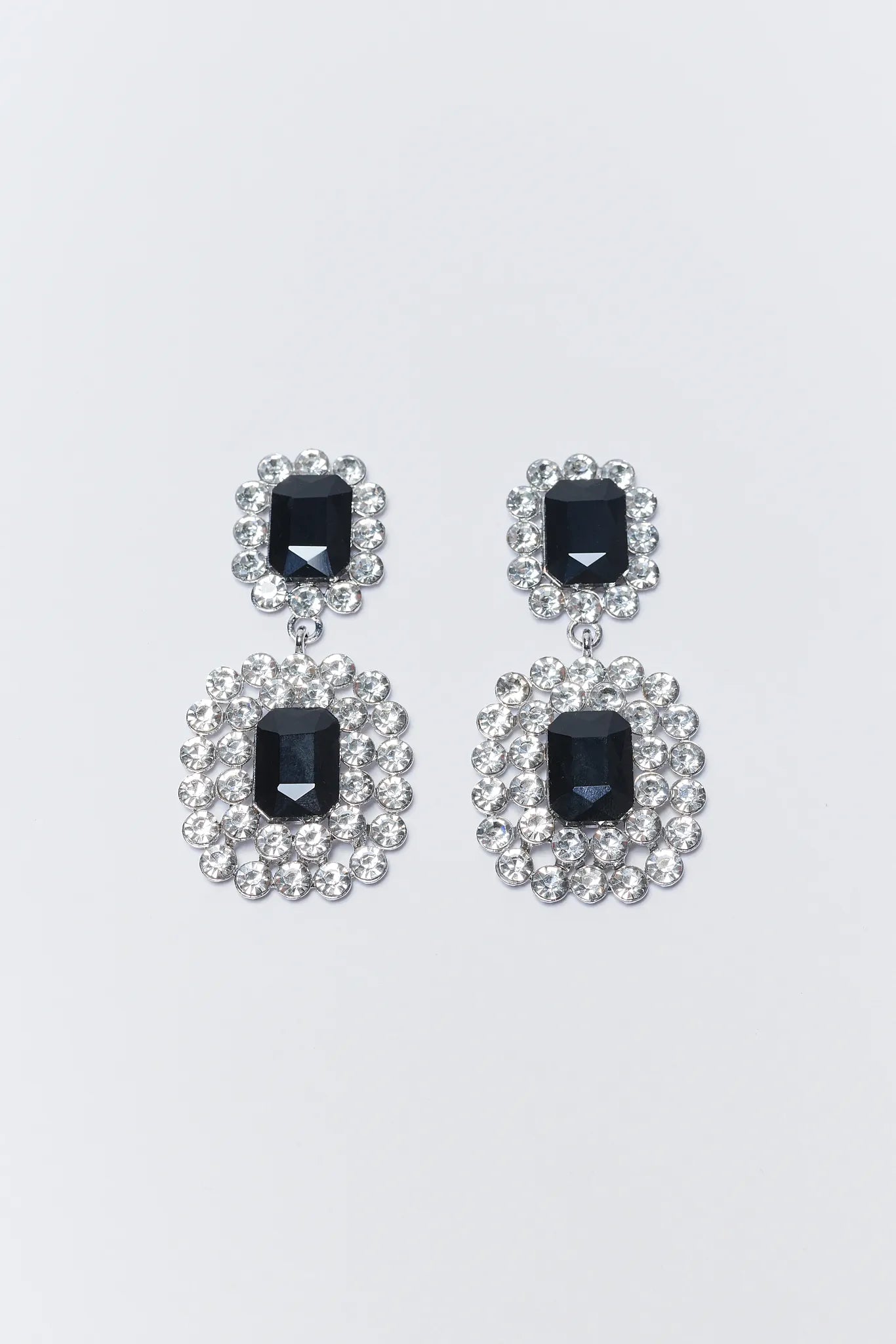 Pair of earrings with black gemstones and silver embellishments on a white background