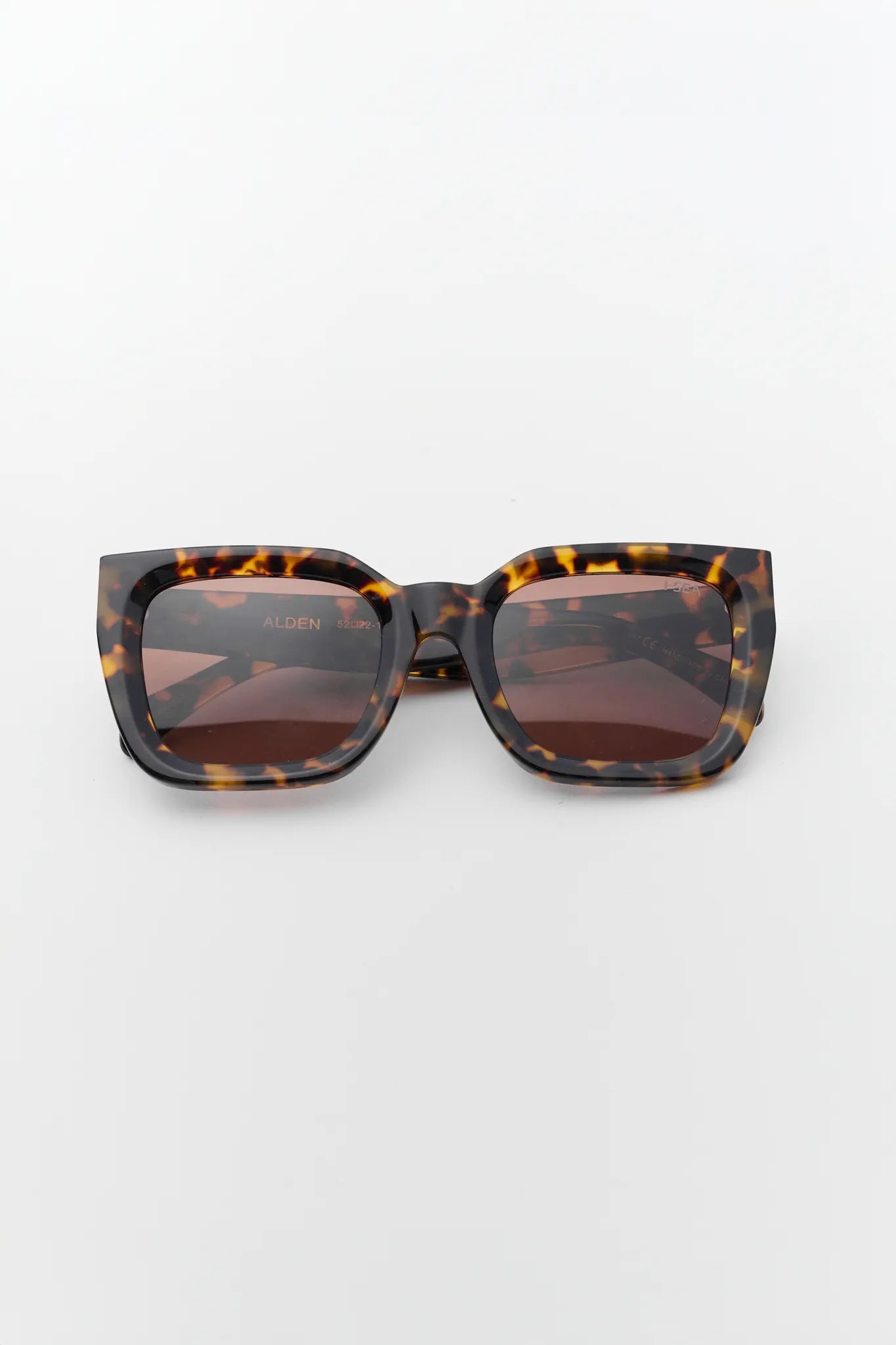 Sunglasses with tortoiseshell frame and brown lenses on a white background