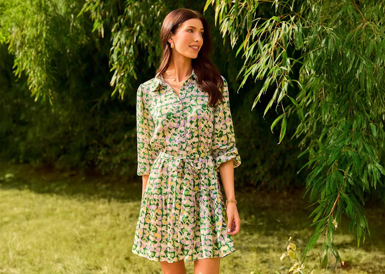 Woman in a floral dress standing in a garden with greenery around