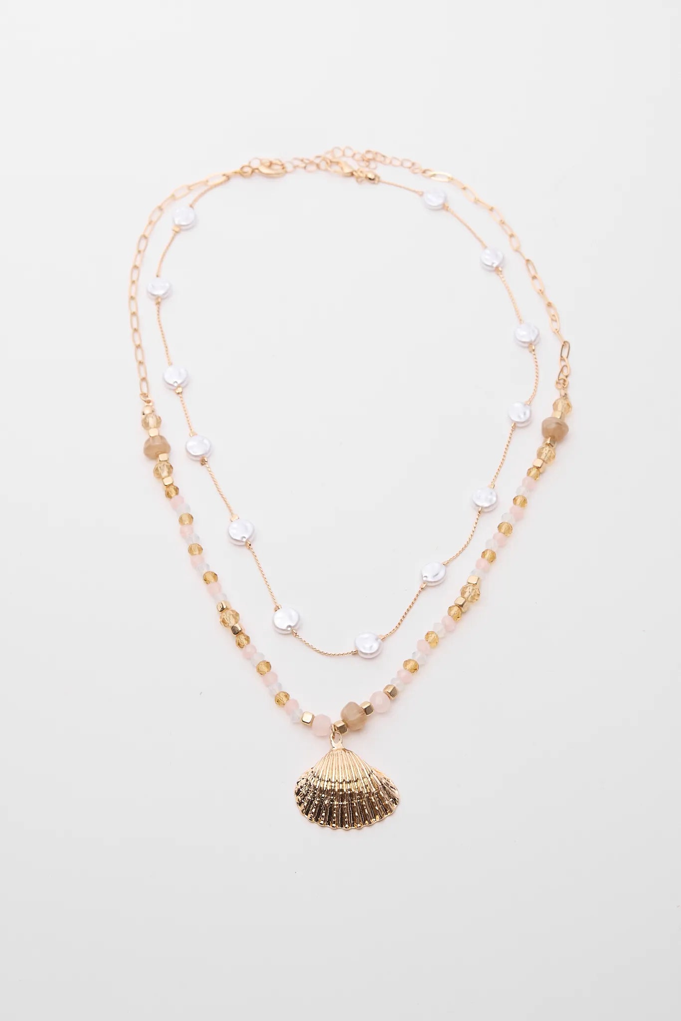 Layered necklace with shell and bead details on a light background