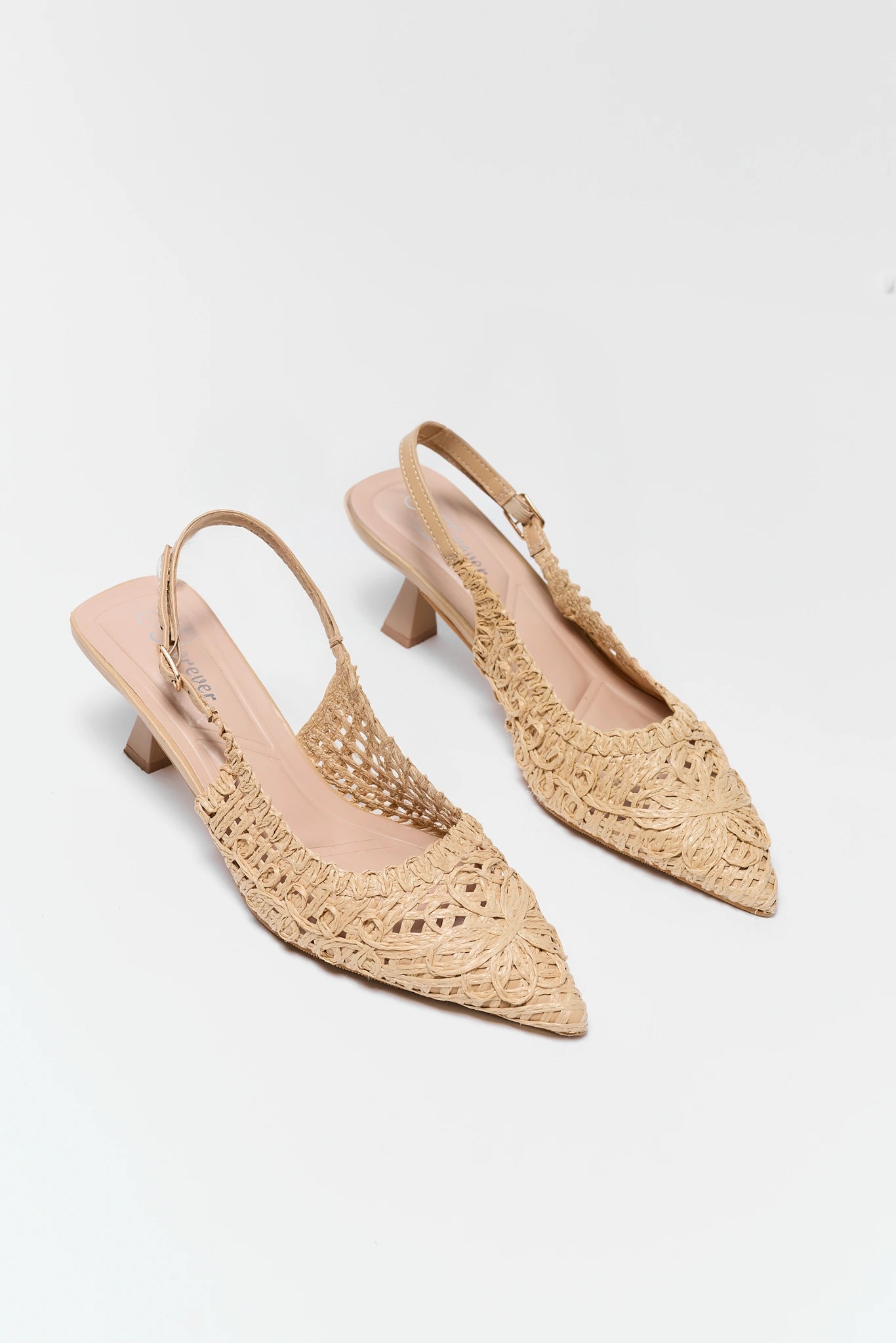 Pair of beige lace slingback shoes on a white background